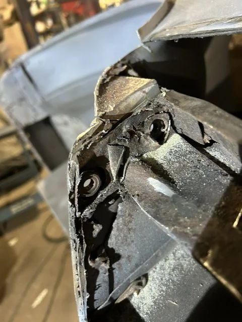 Close-up of a damaged metal car bumper with visible screws and rough edges.