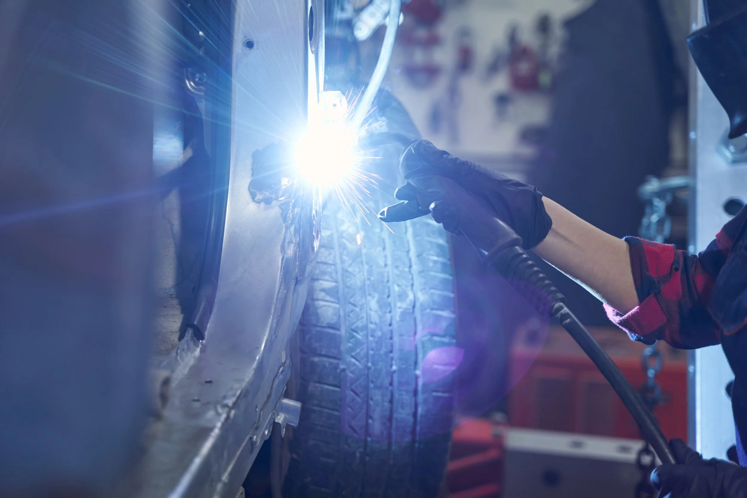 A person wearing a black glove welding metal, creating bright sparks.