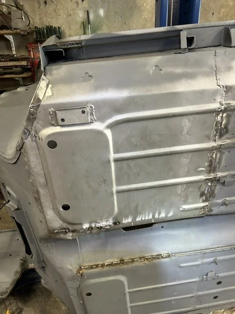 Close-up of a metal car door with visible welding and patches.