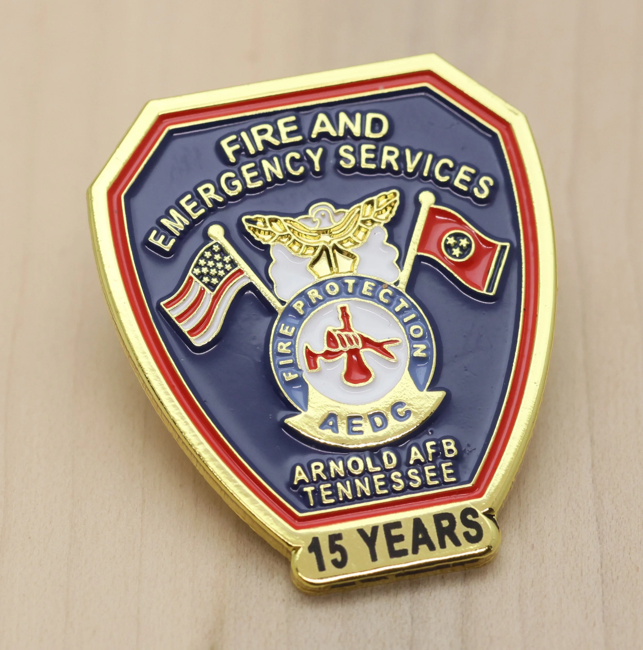 A years of service pin with a firefighter emblem, featuring a shield shape, American flags, a firefighter's helmet, and text indicating 15 years of service in Memphis, Tennessee.