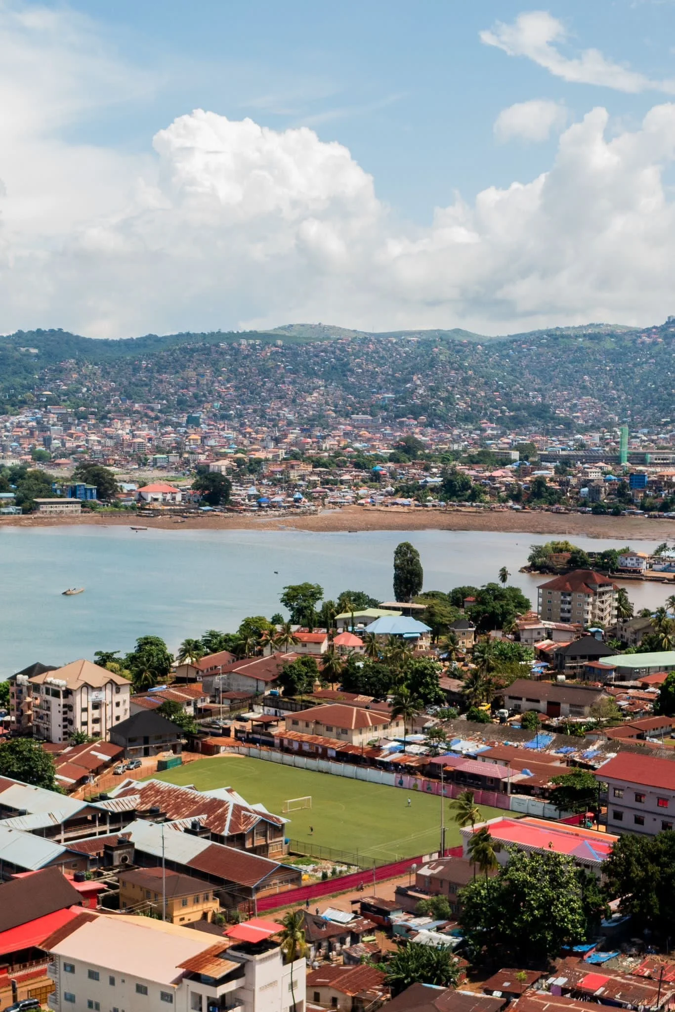 Udsigt over Murray Town i Freetown, Sierra Leone med byen, havet, fodboldbanen og bjergene i baggrunden.