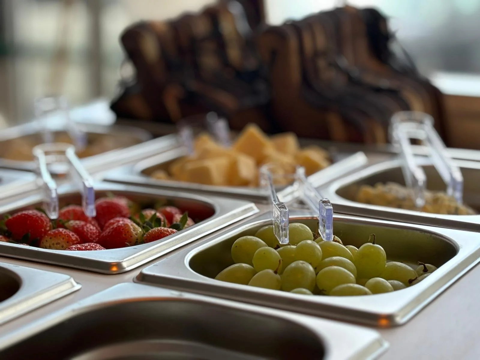 Assorted fresh fruits including strawberries, green grapes, pineapple, and others in a buffet station.