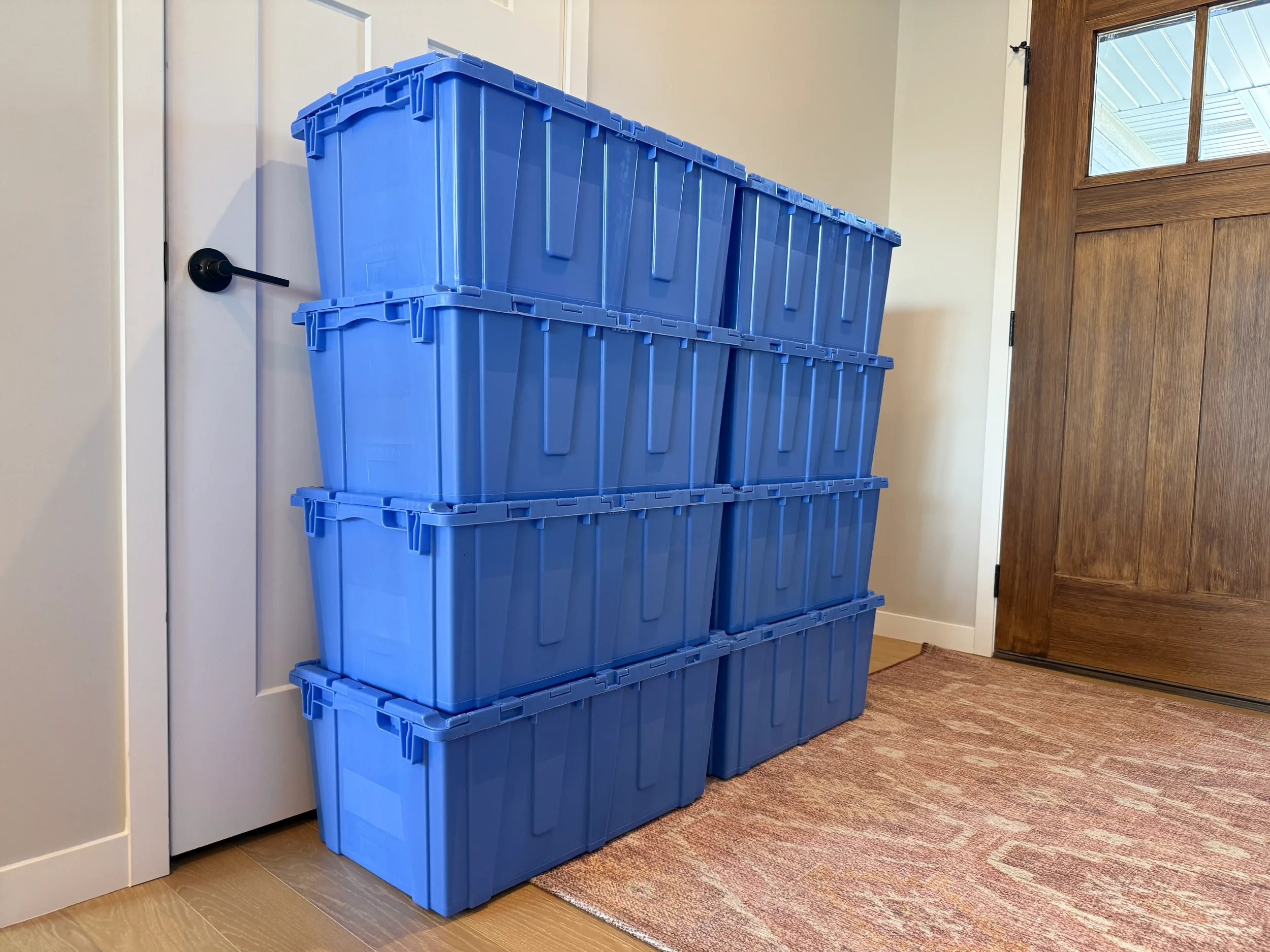 Blue moving totes stacked near a home entryway door — Totes to Go delivers reusable rental totes to your door in Kearney, NE