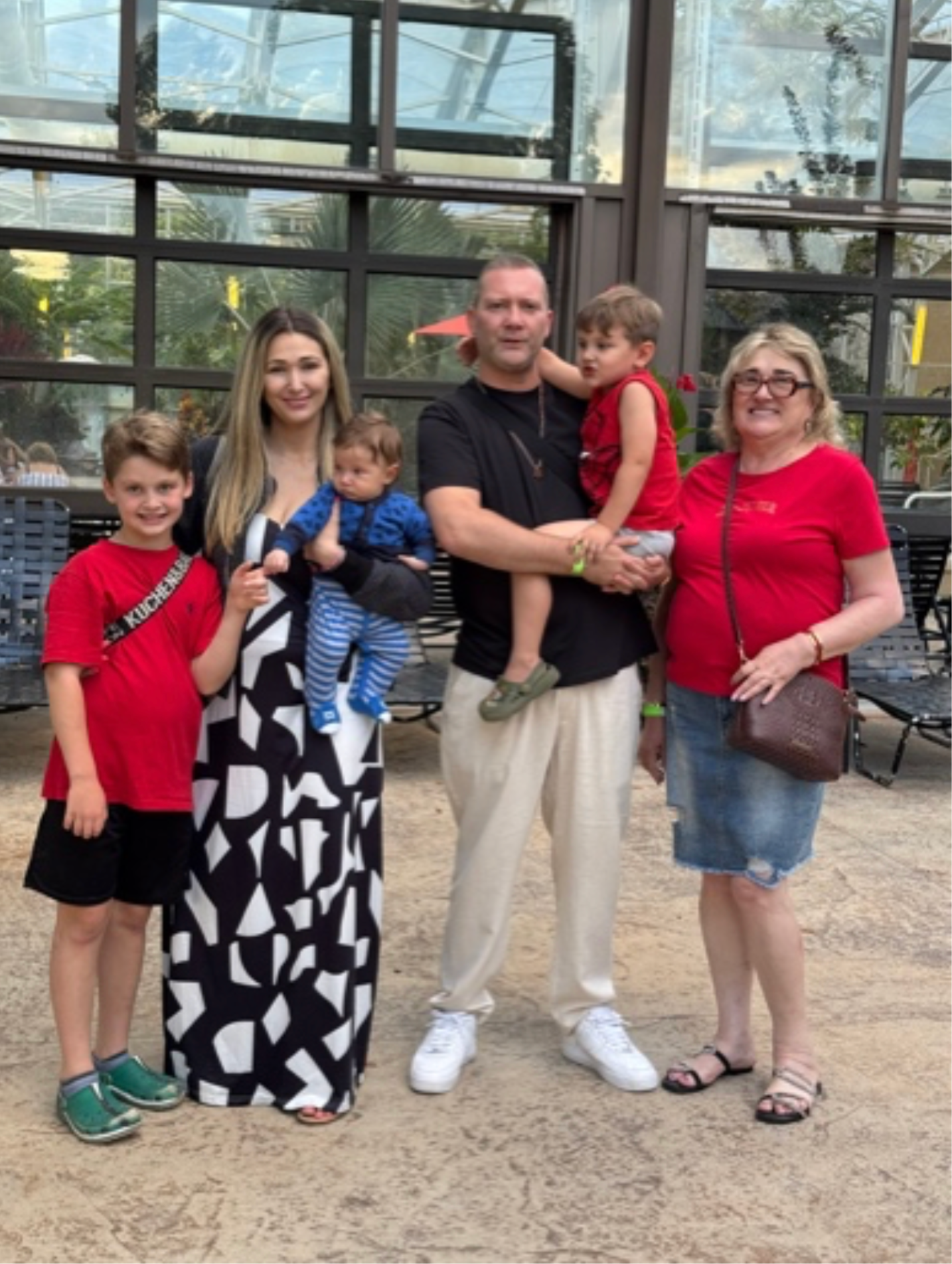 A family group posing together outdoors in front of a glass building.