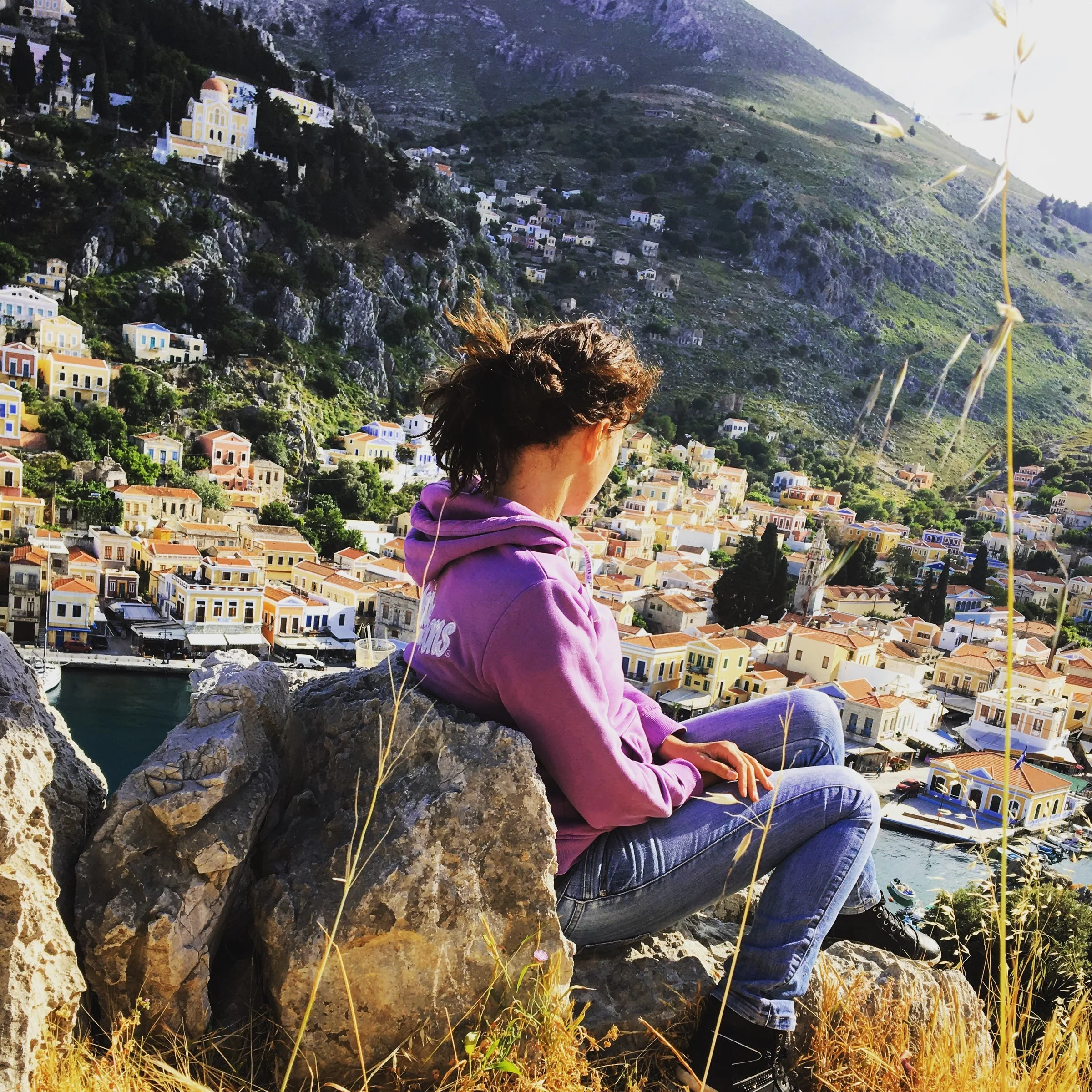 Portrait of photographer Eleni Charitou sitting thoughtfully amidst the rustic nature and warm light of the Aegean.