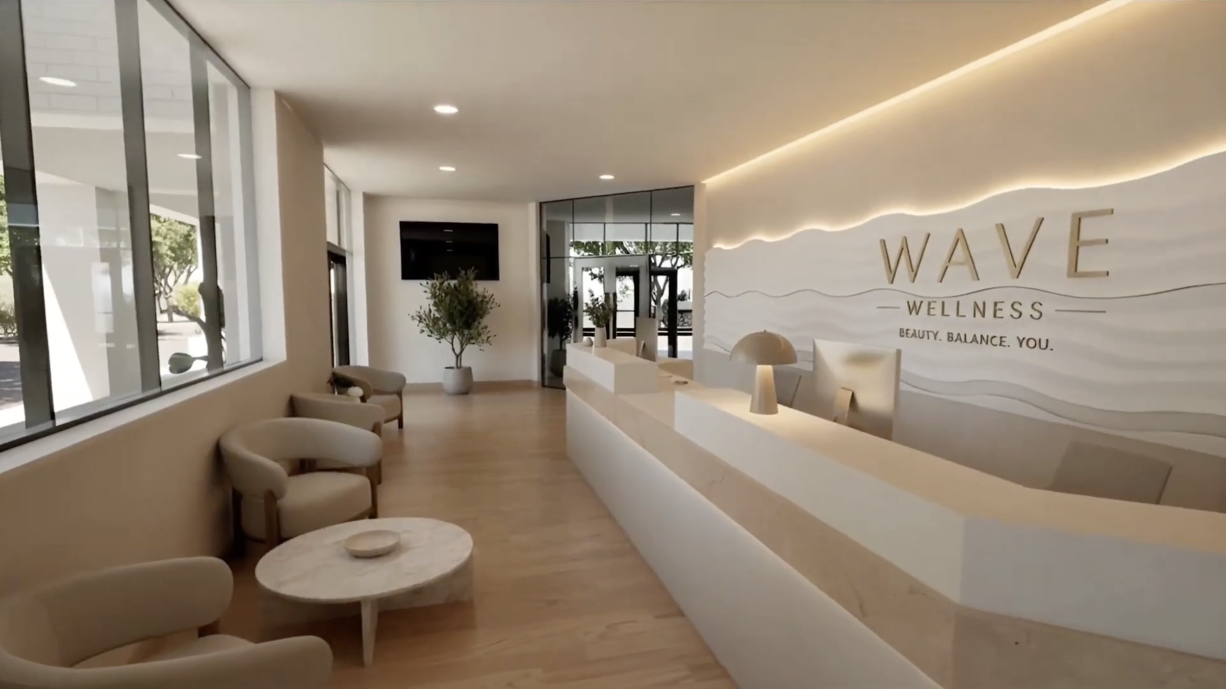 Modern wellness center reception area with white curved desk, beige chairs, indoor plants, large windows, and a wall with the words "WAVE WELLNESS" and the slogan "BEAUTY. BALANCE. YOU." illuminated with soft lighting.