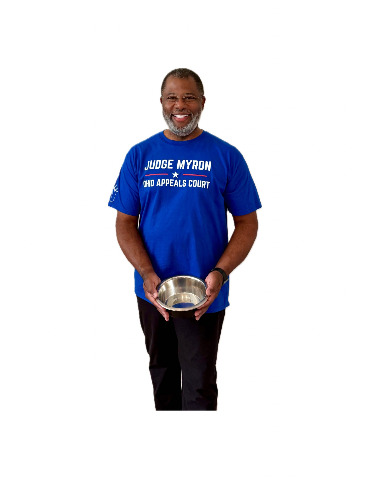 A smiling man with glasses and a beard wearing a blue T-shirt that says 'Judge Myron Ohio Appeals Court' and holding a metal bowl in front of him against a plain white background.