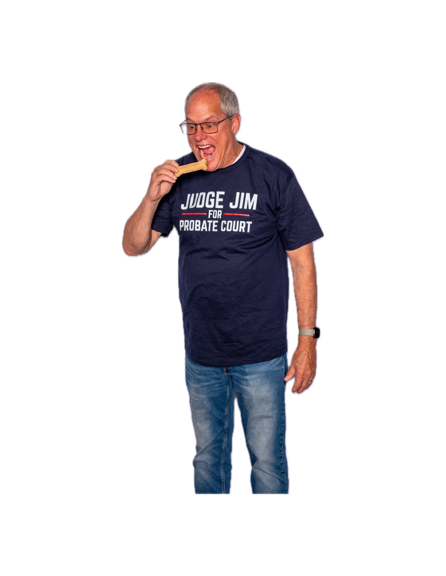 An older man with gray hair and glasses wearing a navy t-shirt that says "JUDGE JIM FOR PROBATE COURT" in white letters, and blue jeans, licking a dog bone