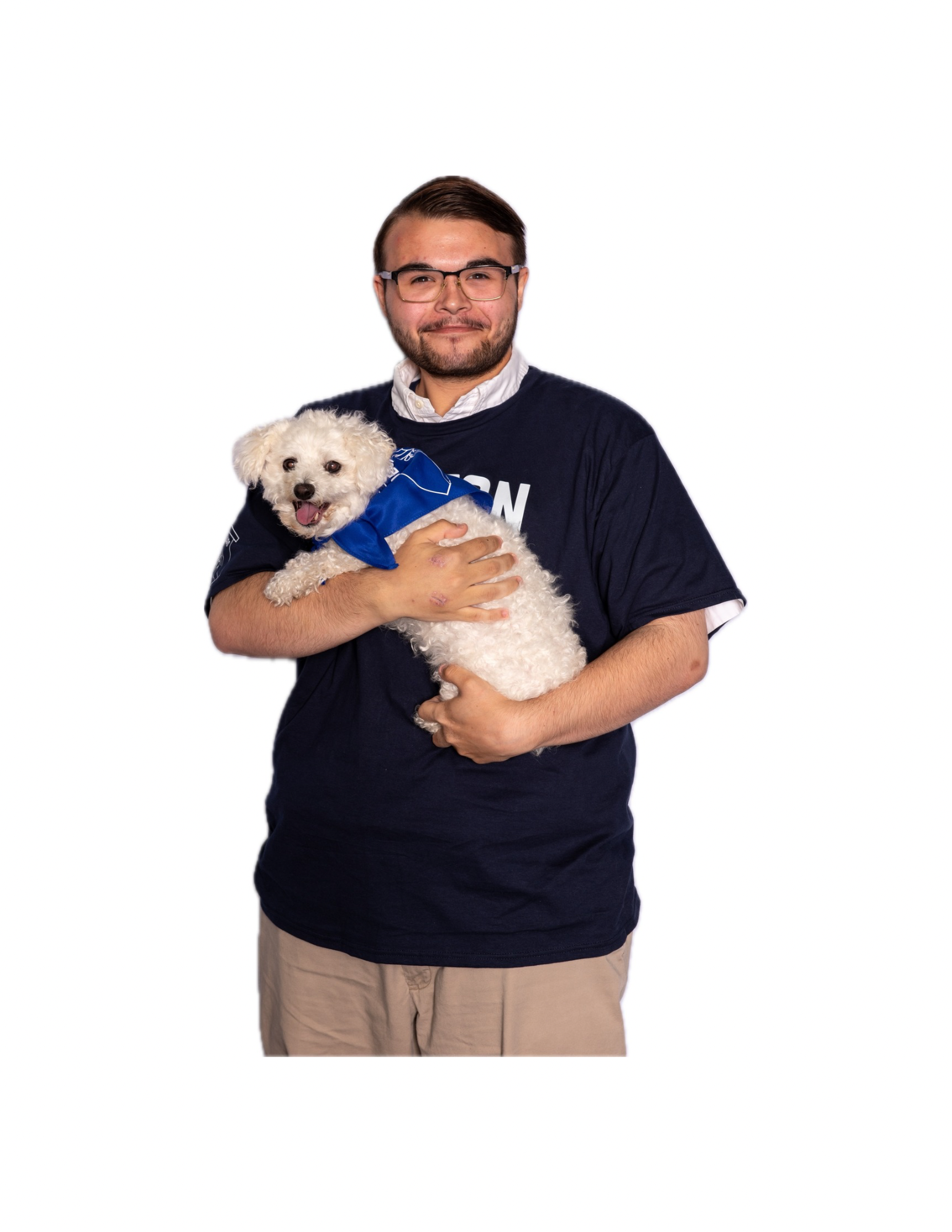 A man with glasses, a beard, wearing a dark blue t-shirt over a white collared shirt, holding a small white dog with curly fur and a blue bandana, against a plain white background.