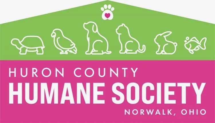 Logo for Huron County Humane Society in Norwalk, Ohio, featuring white outlines of six different animals on a pink and green background with a paw print and heart symbol.