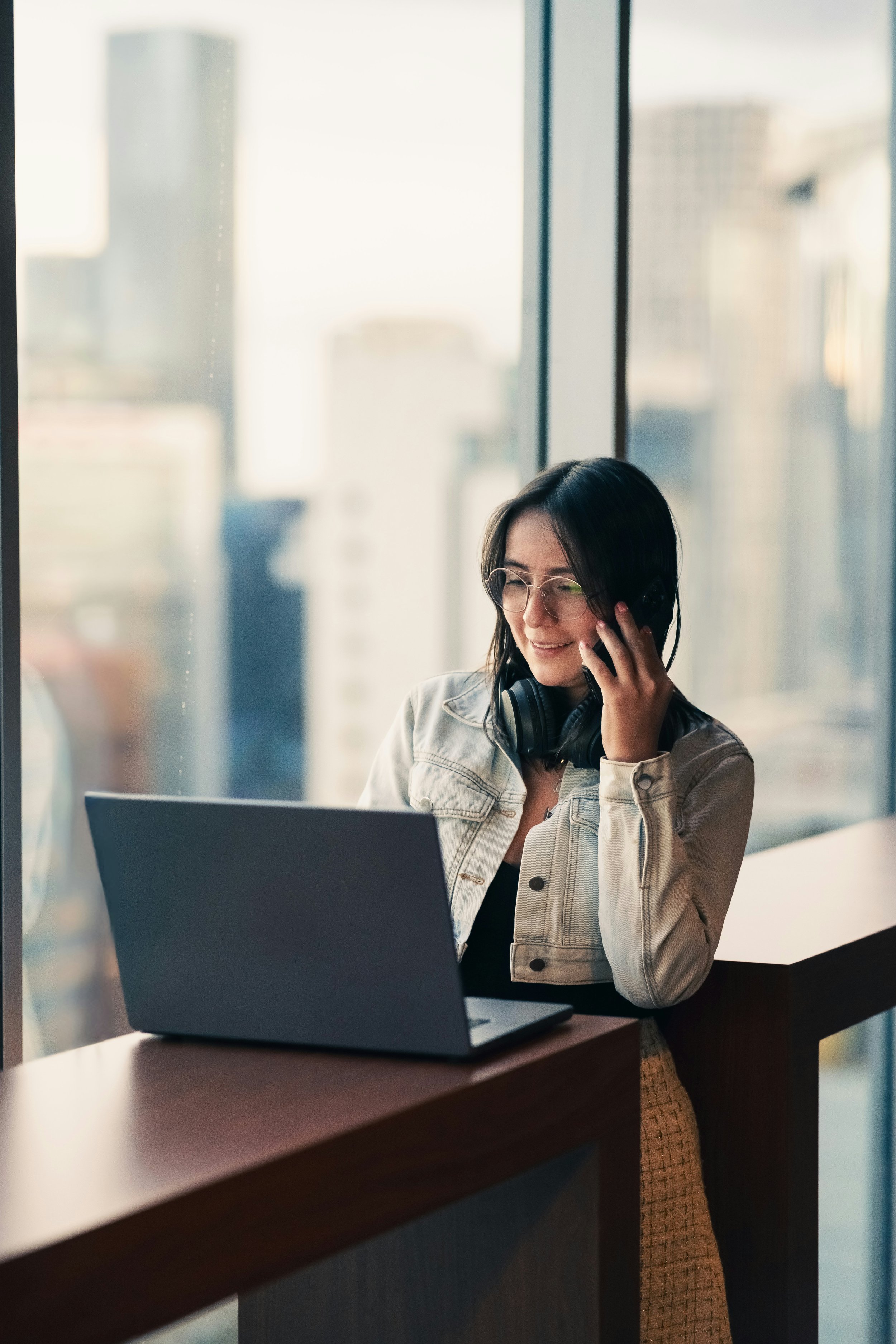 Woman talking on the phone while looking at her laptop screen.