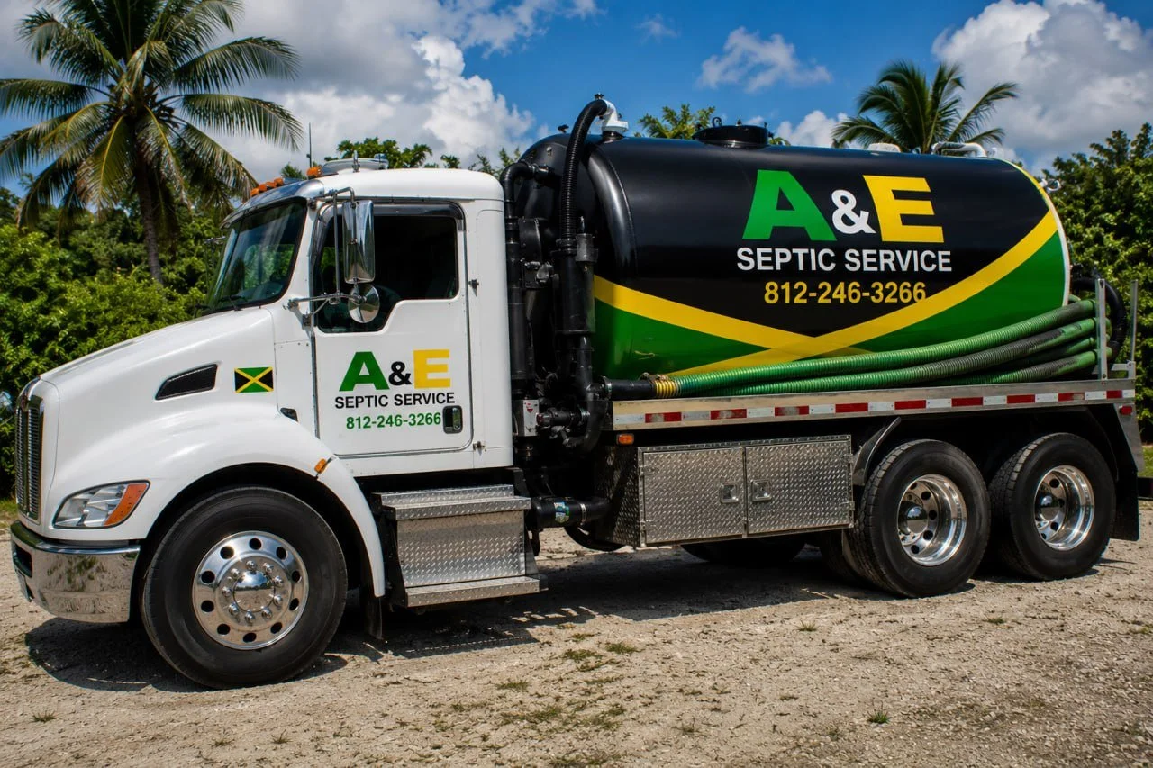 A septic service truck labeled 'A&E Septic Service' with a green, yellow, and black color scheme, parked on a dirt area with palm trees and a partly cloudy sky in the background.