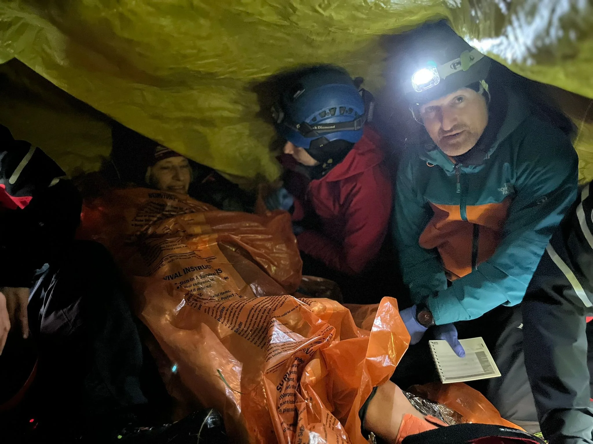 Group of rescue workers inside a confined space wearing helmets and headlamps, preparing for a rescue operation.
