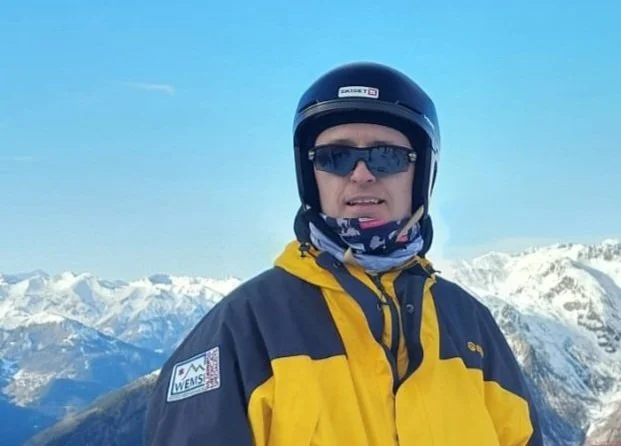 Person wearing a helmet and sunglasses in a snowy mountain landscape