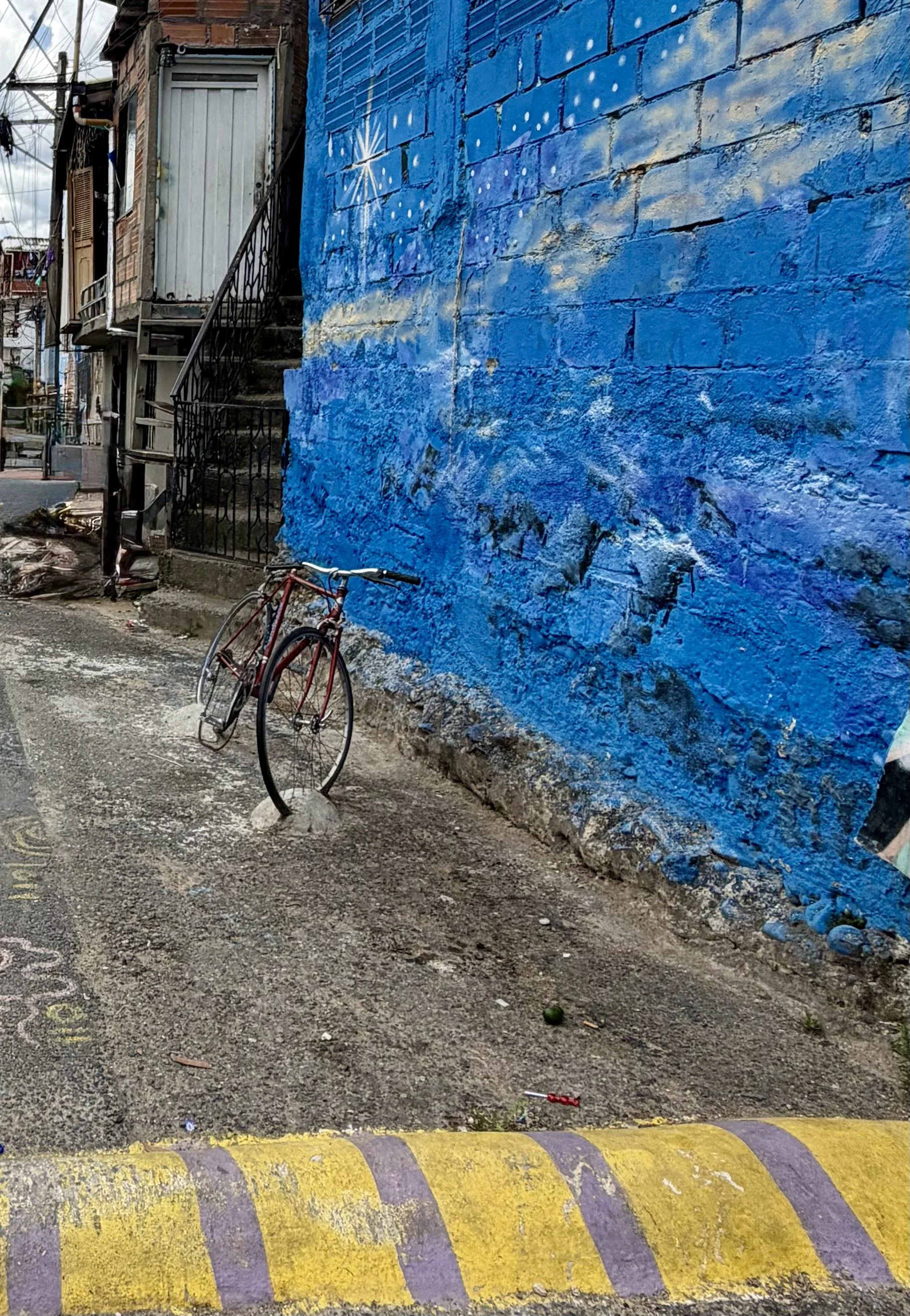Bicycle parked against a bright blue mural wall on a street corner