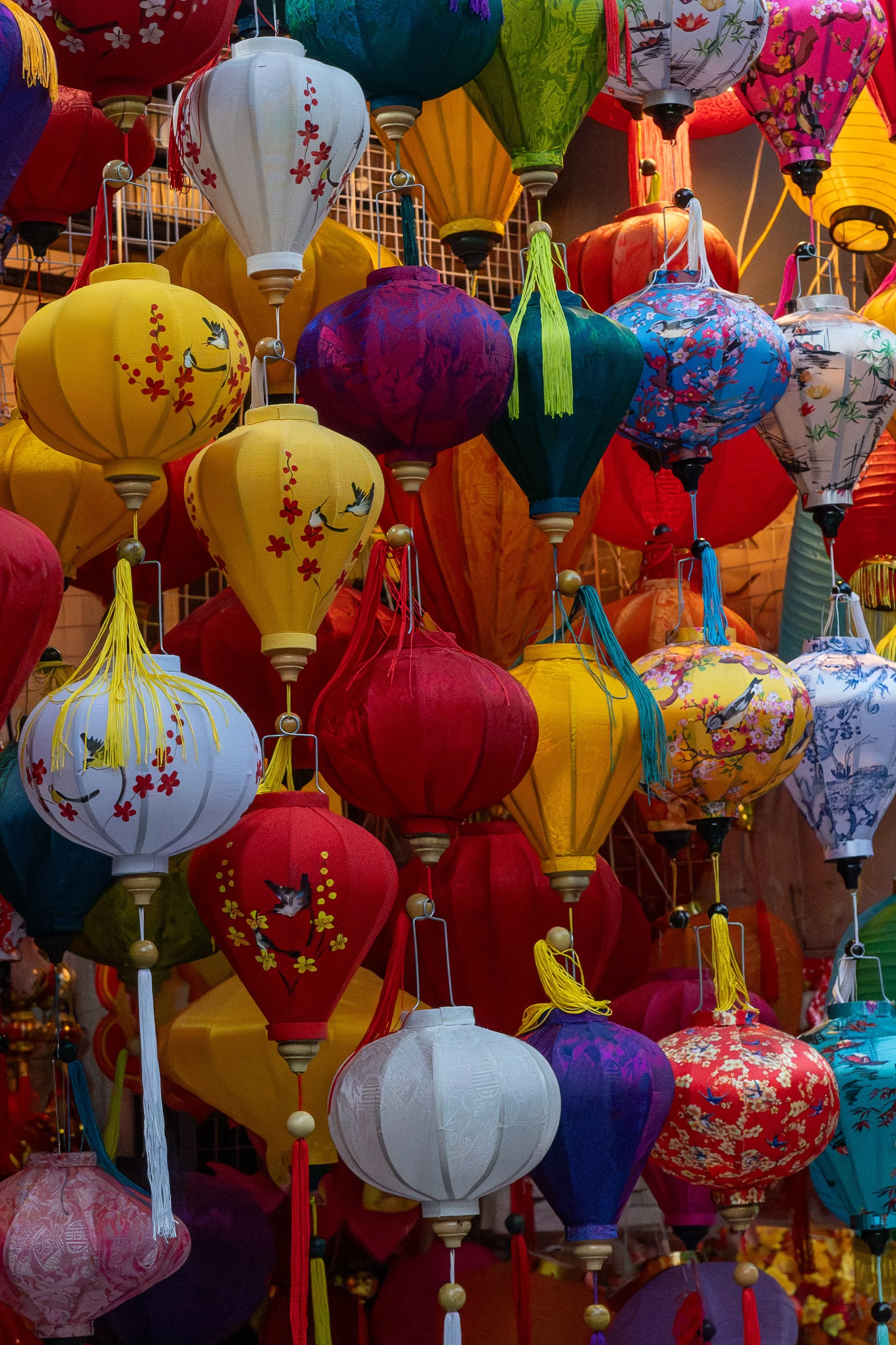 Colorful lanterns with various designs including floral and bird motifs, hanging in a display.