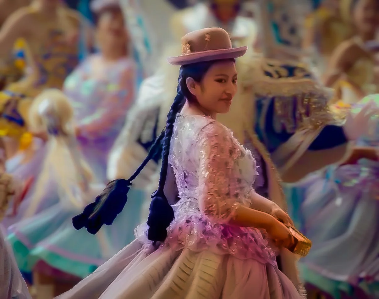 Young Bolivian girl in traditional dress with a pink bowler hat and long braided hair at a festival parade