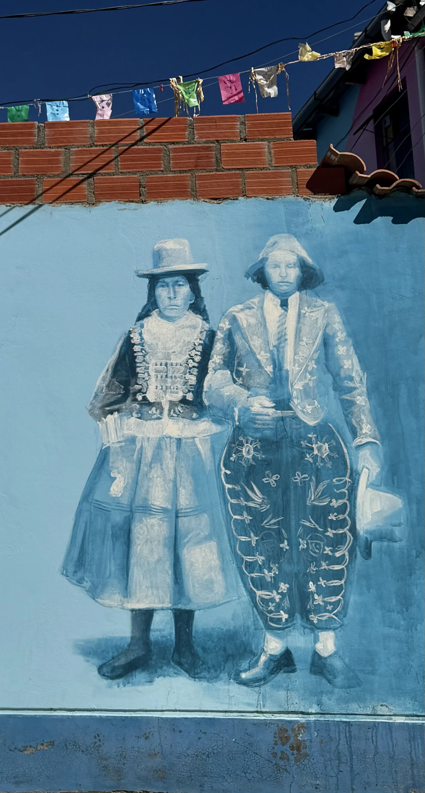 Monochrome blue mural of a couple in traditional dress beneath festive banners