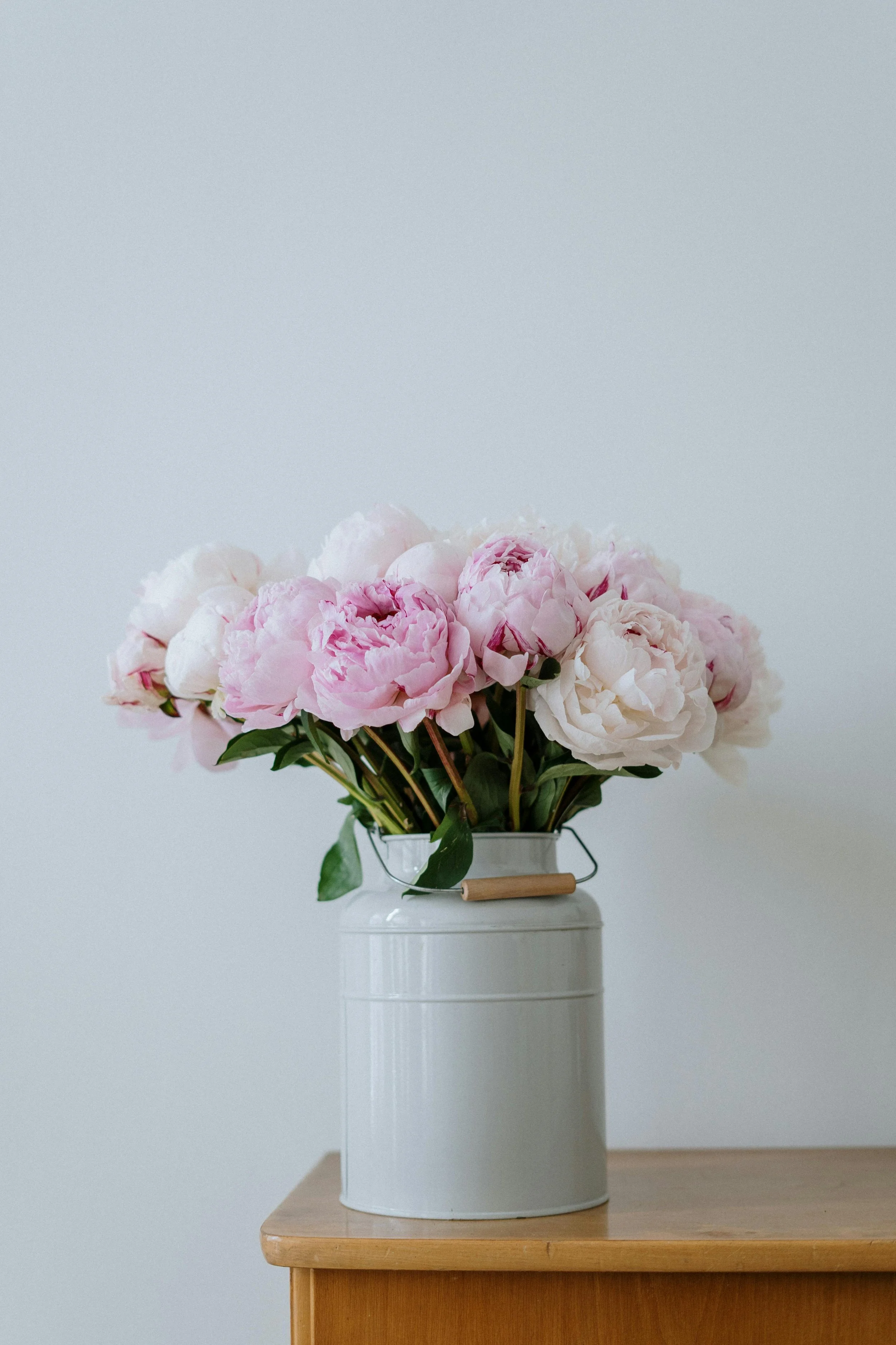 Soft pink and white peonies in a white vase, creating a fresh and hopeful feel beside the About page text.