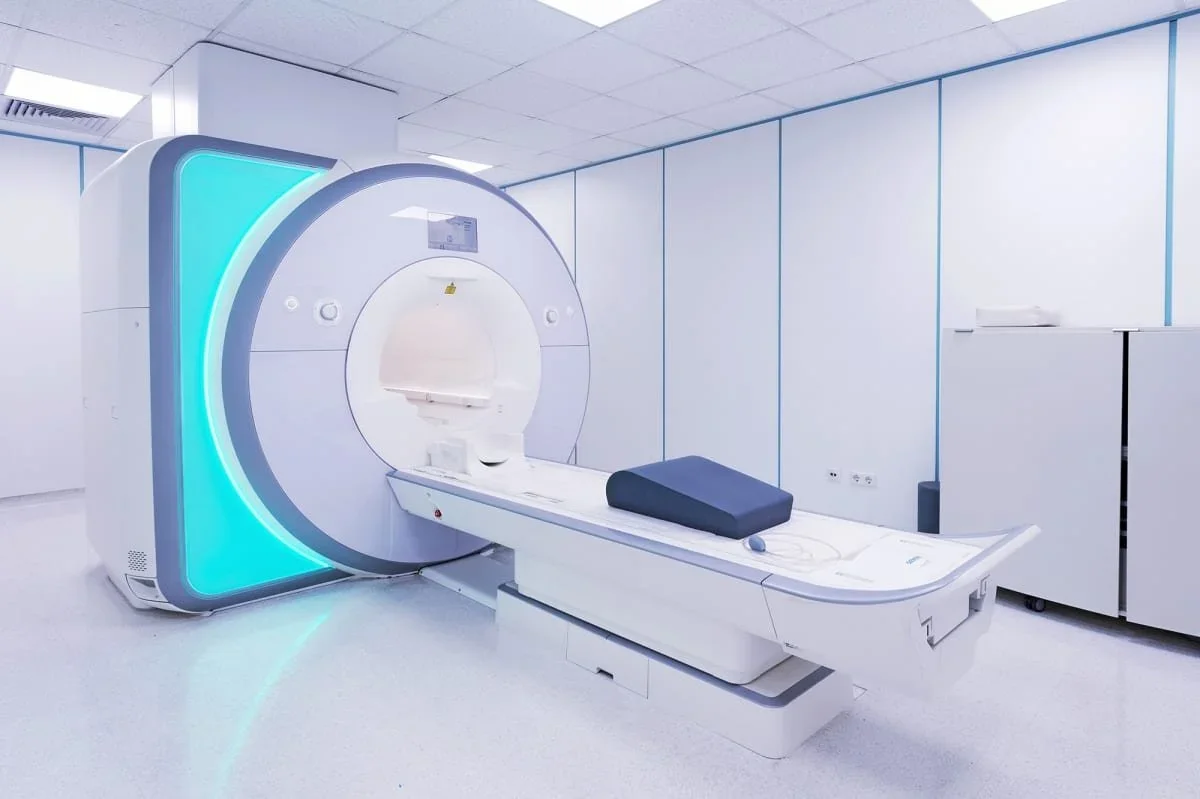 Modern MRI machine in a clinical room with white walls and ceiling.