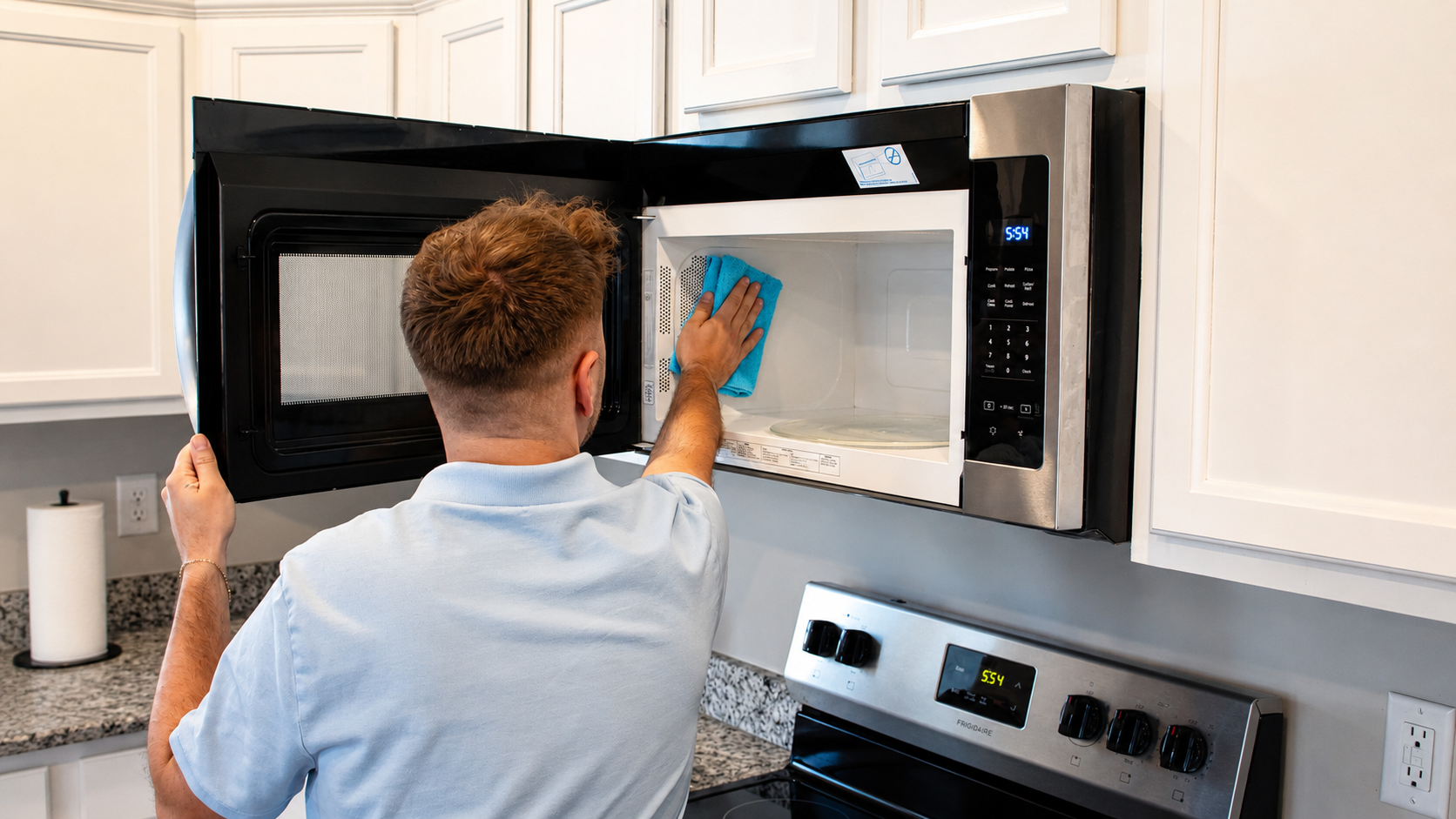 Cleaning specialist wiping the interior of a microwave with a microfiber cloth.