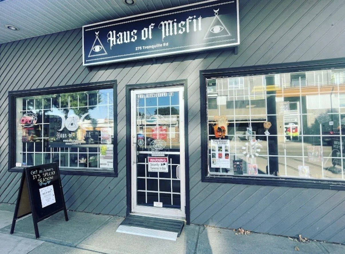 The storefront of Haus of Mist with a signboard, large windows with decorations, and a glass door with warning signs. There is a blackboard sign outside promoting laser treatments.