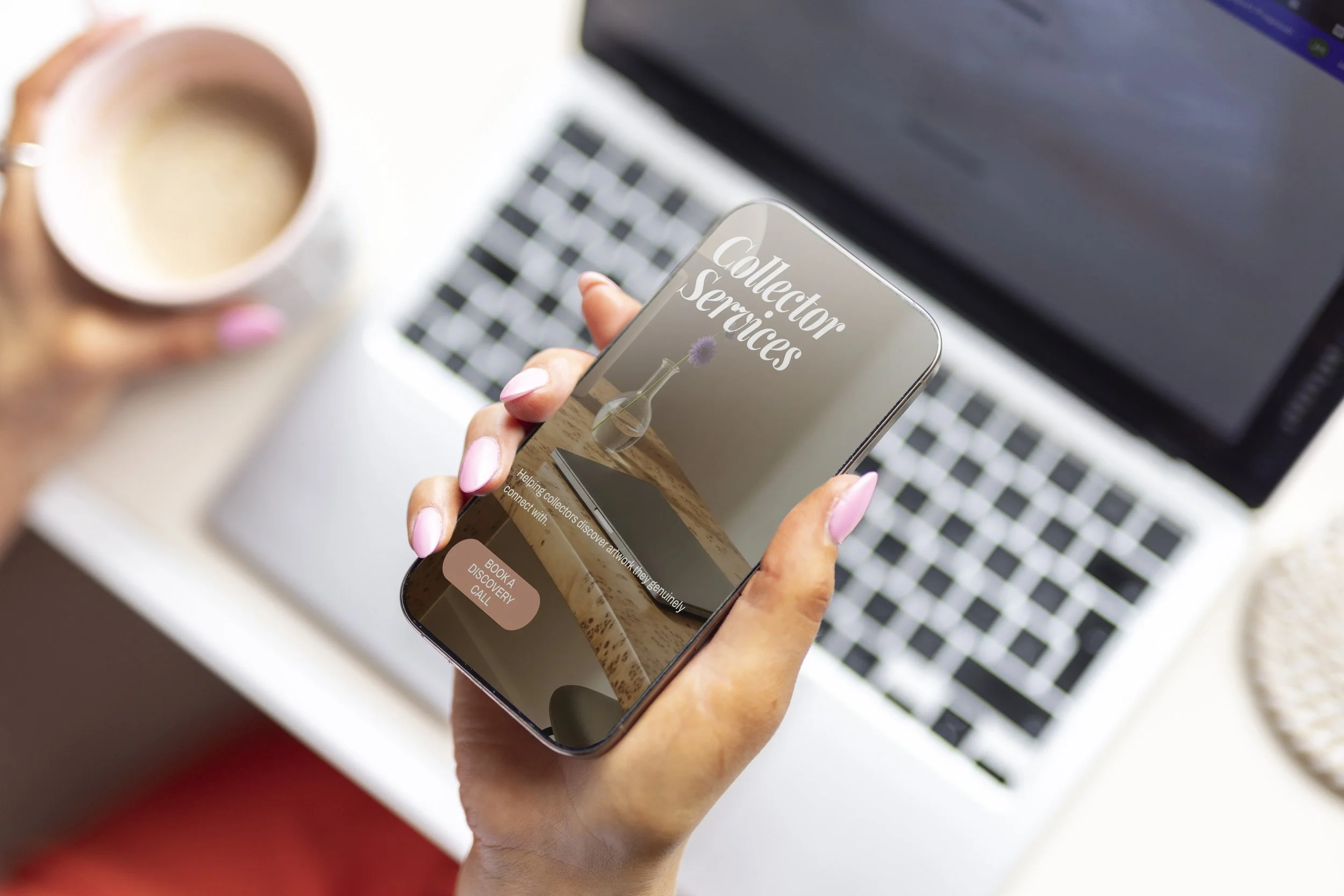 Person holding a smartphone displaying a website called 'Collector Services' with a background of a laptop keyboard and a mug full of coffee in the background.