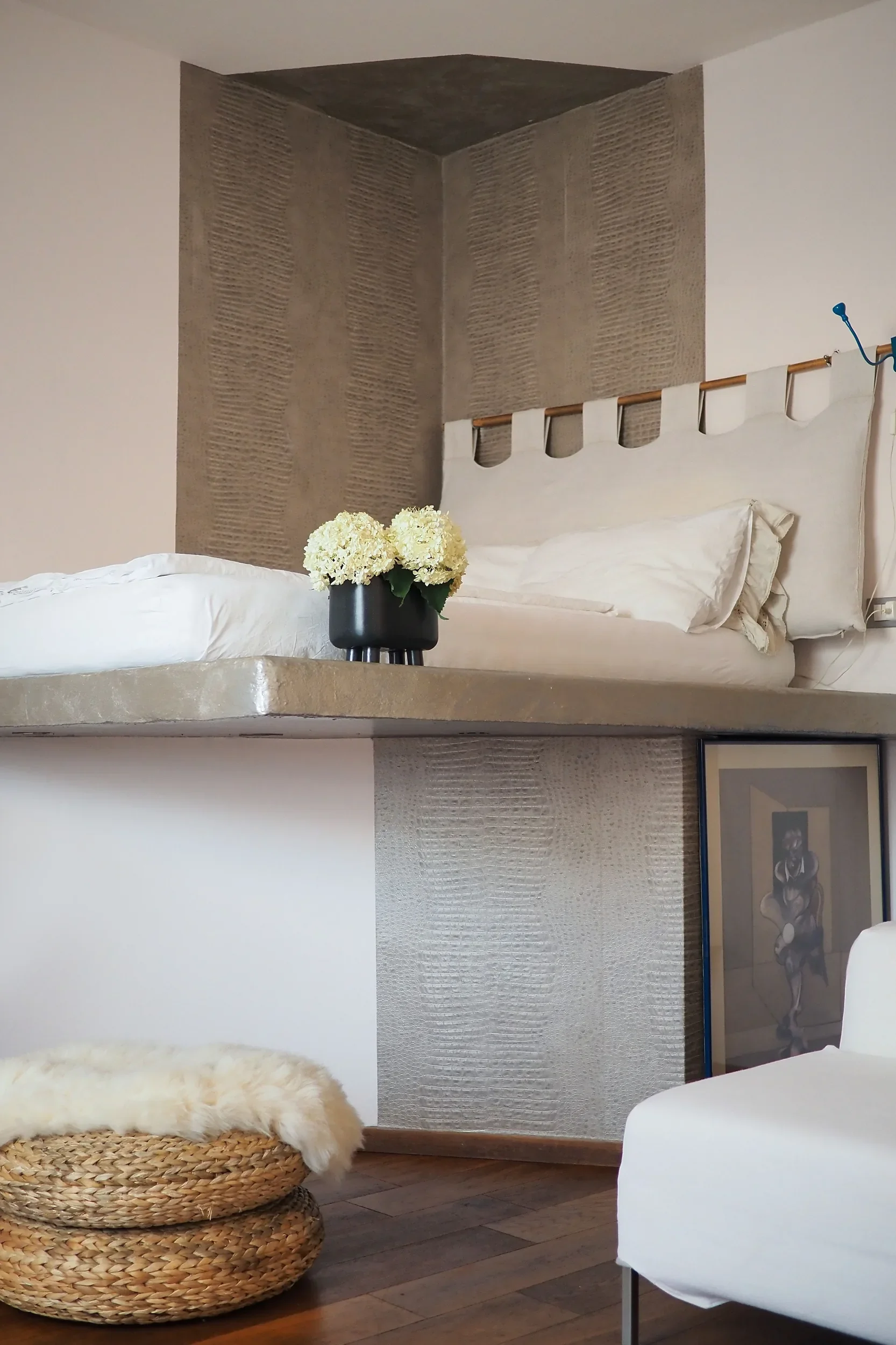 Mezzanine bed with rattan headboard and a black vase, the Francis Bacon artwork framed below