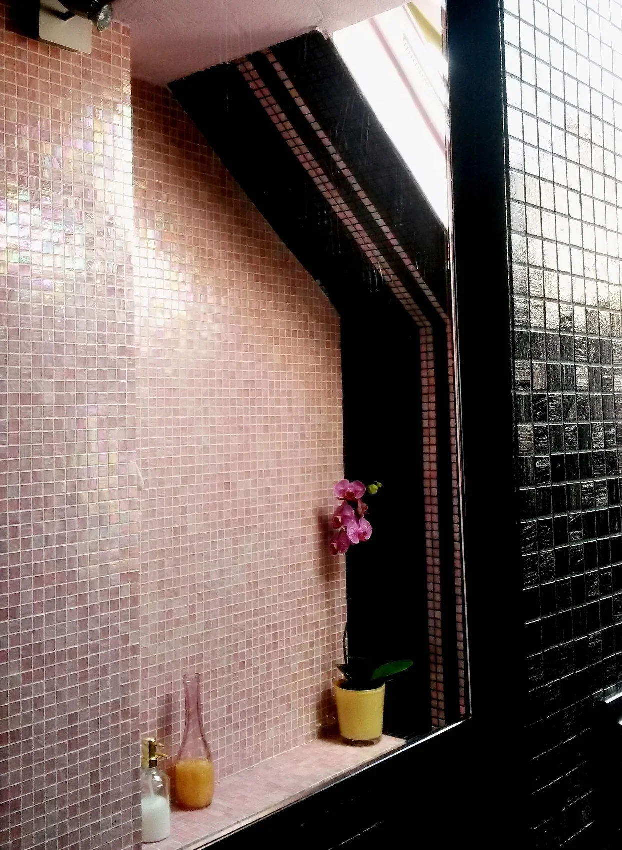 Bisazza mosaic niche with an orchid and amber bottles beside the mirror