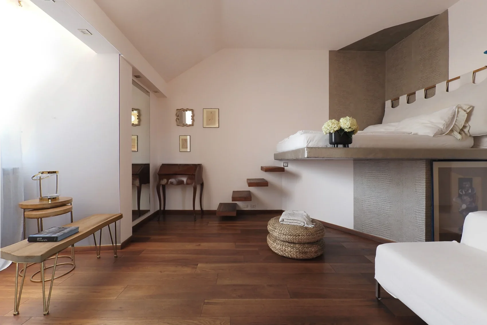 The open space: mezzanine bed above the suspended wooden staircase, with a Francis Bacon artwork framed below the bed, Milano