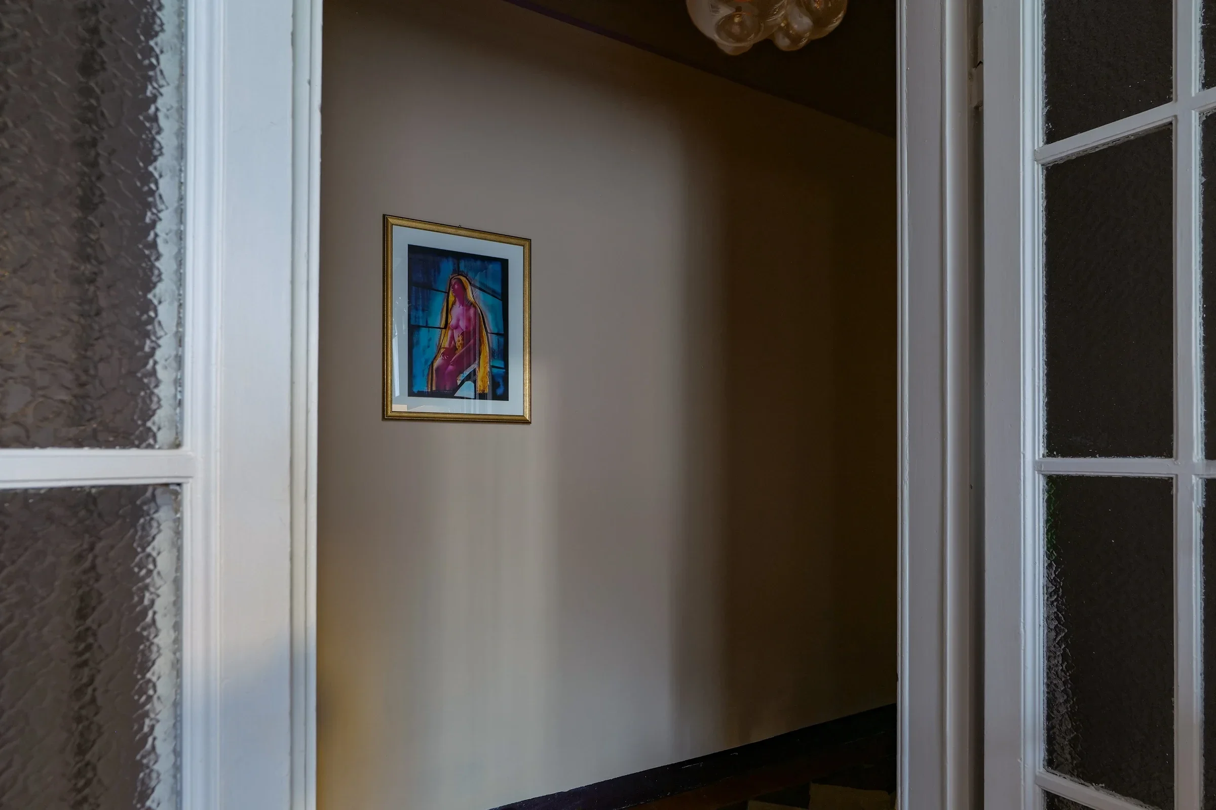 The kitchen corner seen through the original glazed doors, with a David LaChapelle artwork on the far wall, Milano