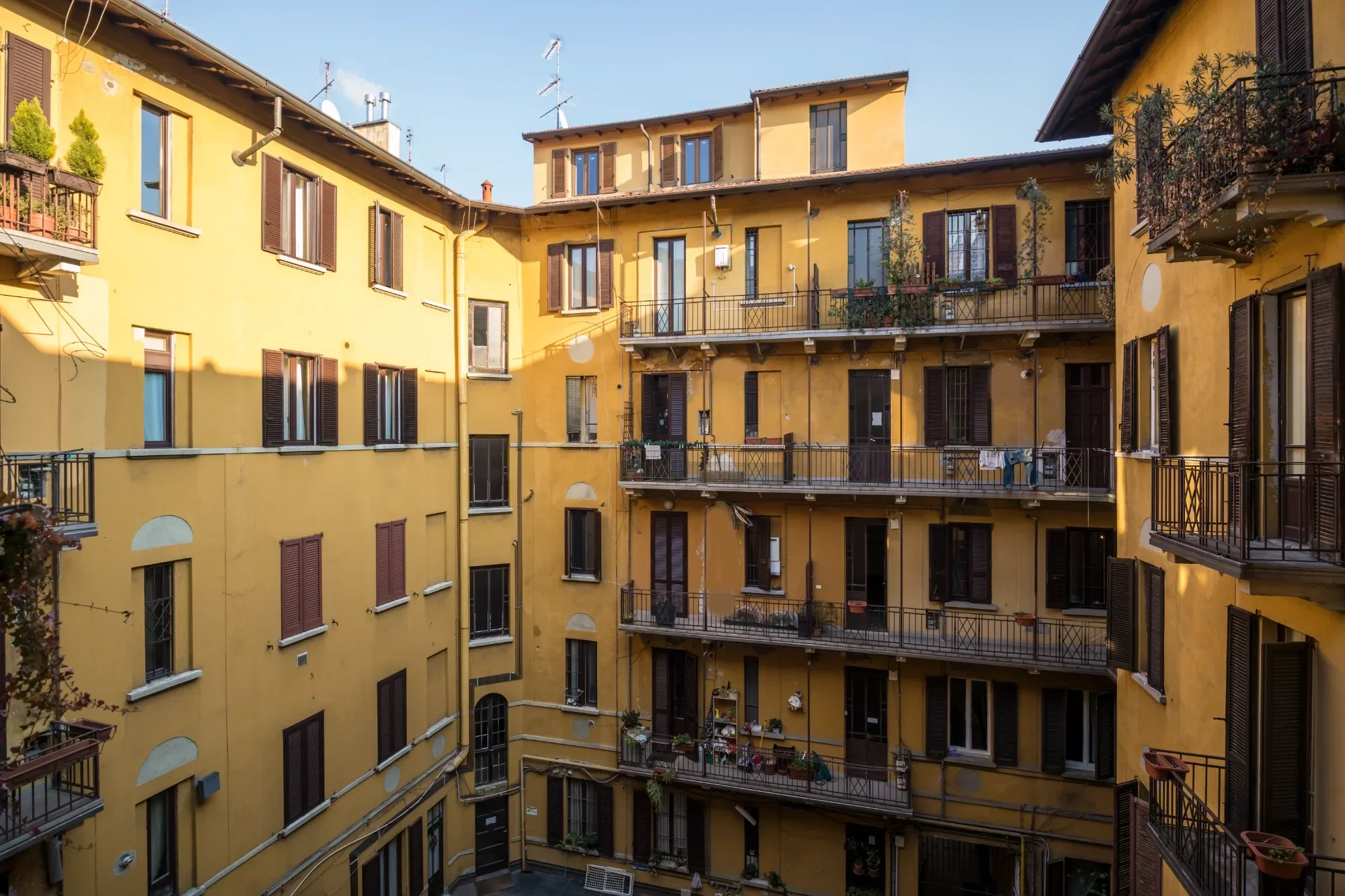 Inner courtyard with yellow facades and wrought-iron balconies, Milano