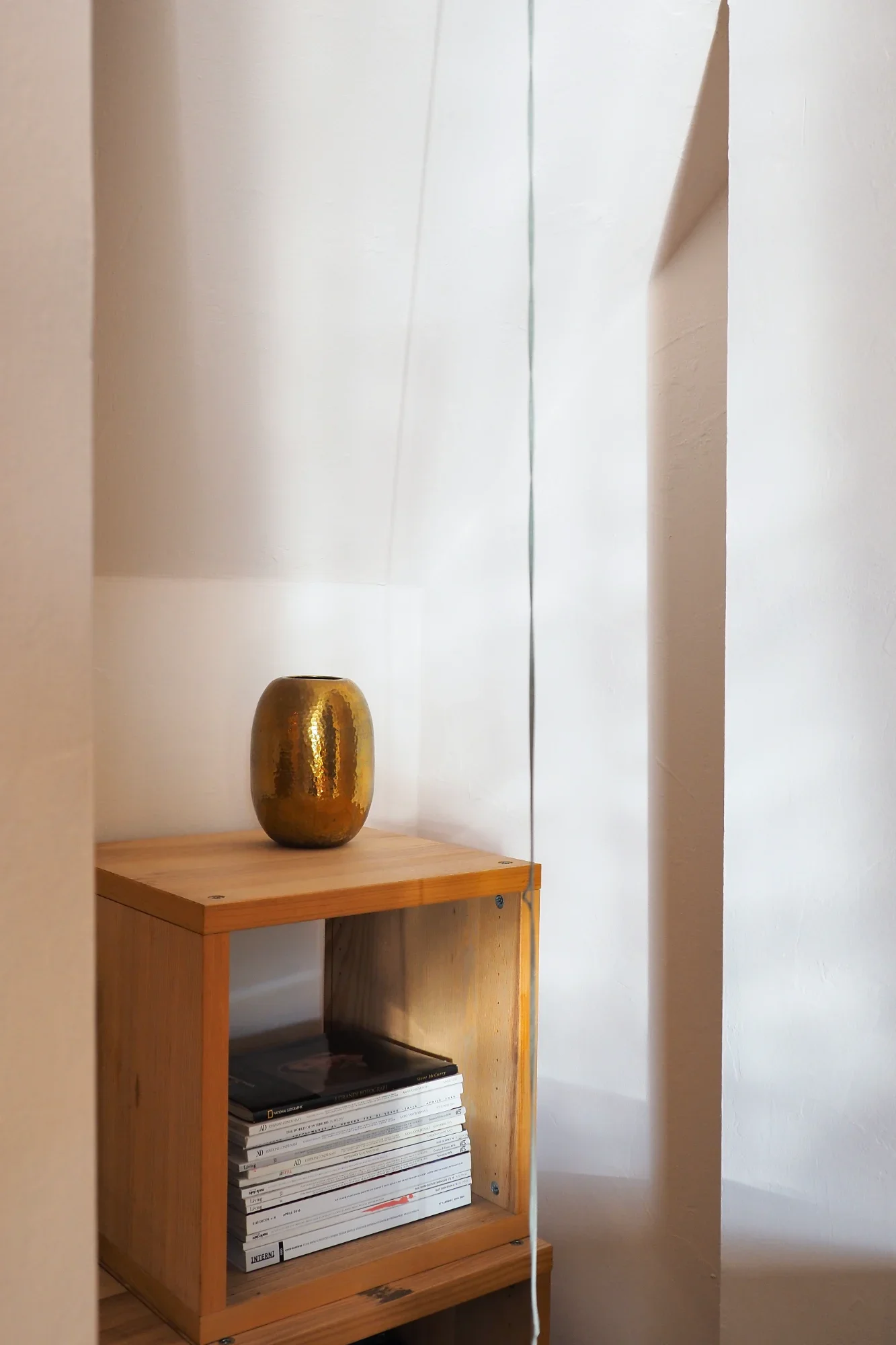 Wall niche with a brass vase and design books