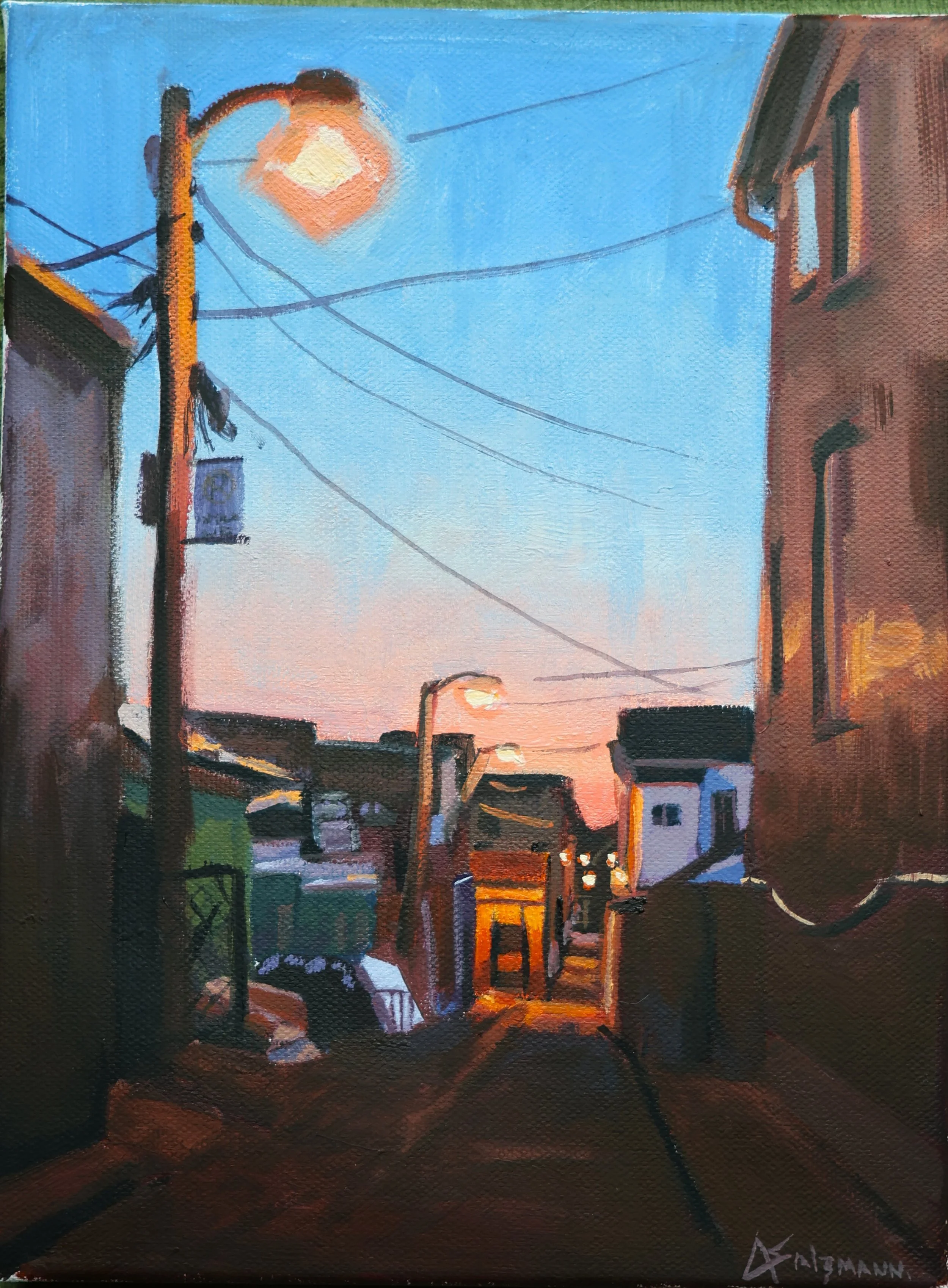 A painting of a sunset viewed from a street, with a utility pole and wires on the left, buildings on both sides, and streetlights illuminated, capturing an urban scene at dusk.