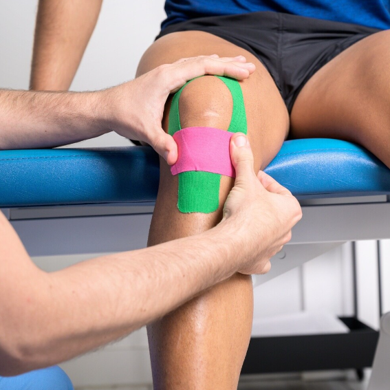 a therapist applying tape to support a client's injured knee joint.