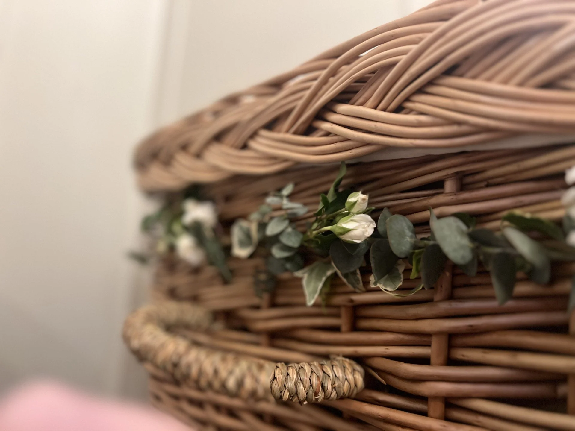 Close-up of a woven wicker basket with greenery and small white flowers.
