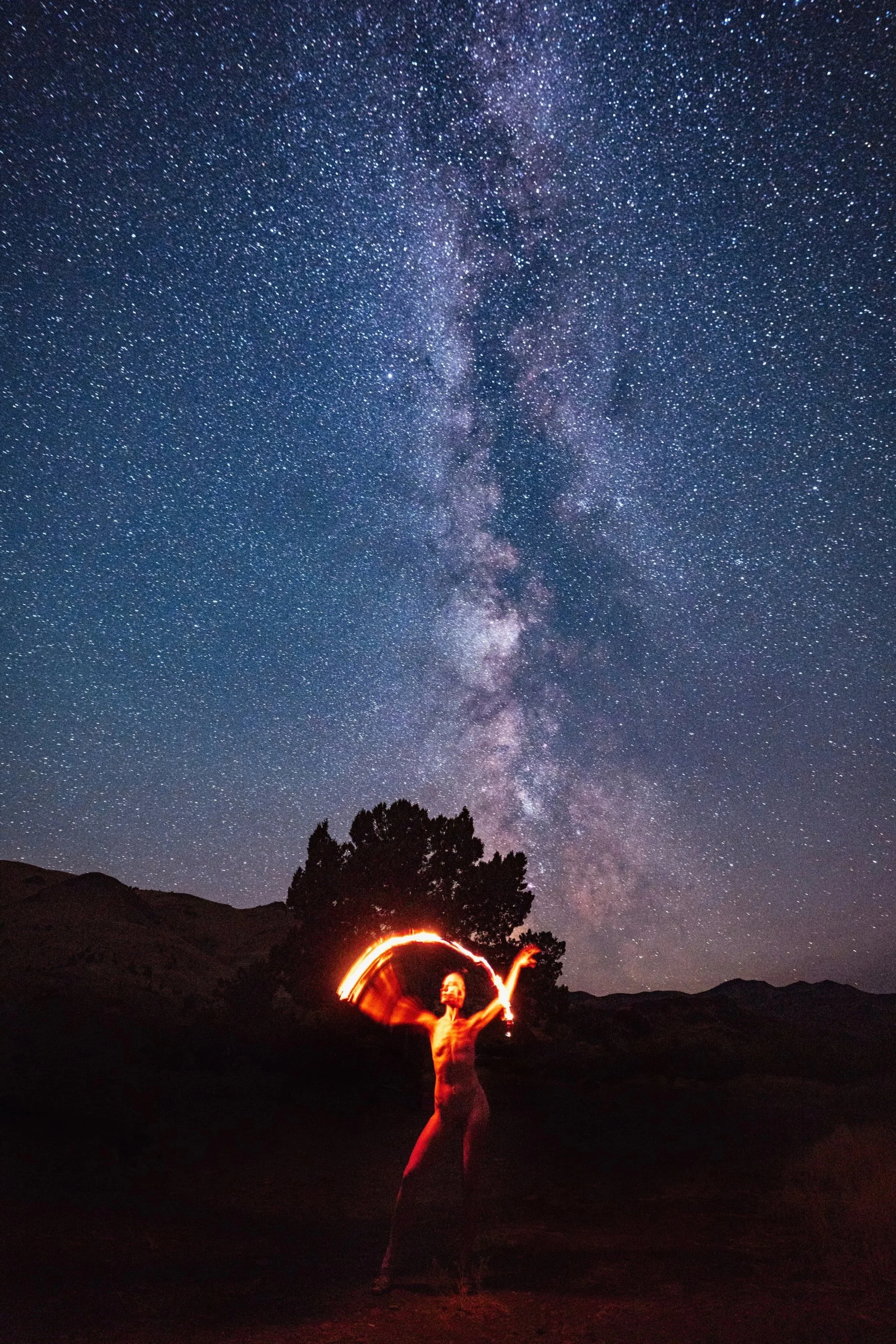  Self portrait of woman spinning fire under the Milky Way galaxy on a dark Montana night, long exposure fine art photography by Missoula Montana photographer.