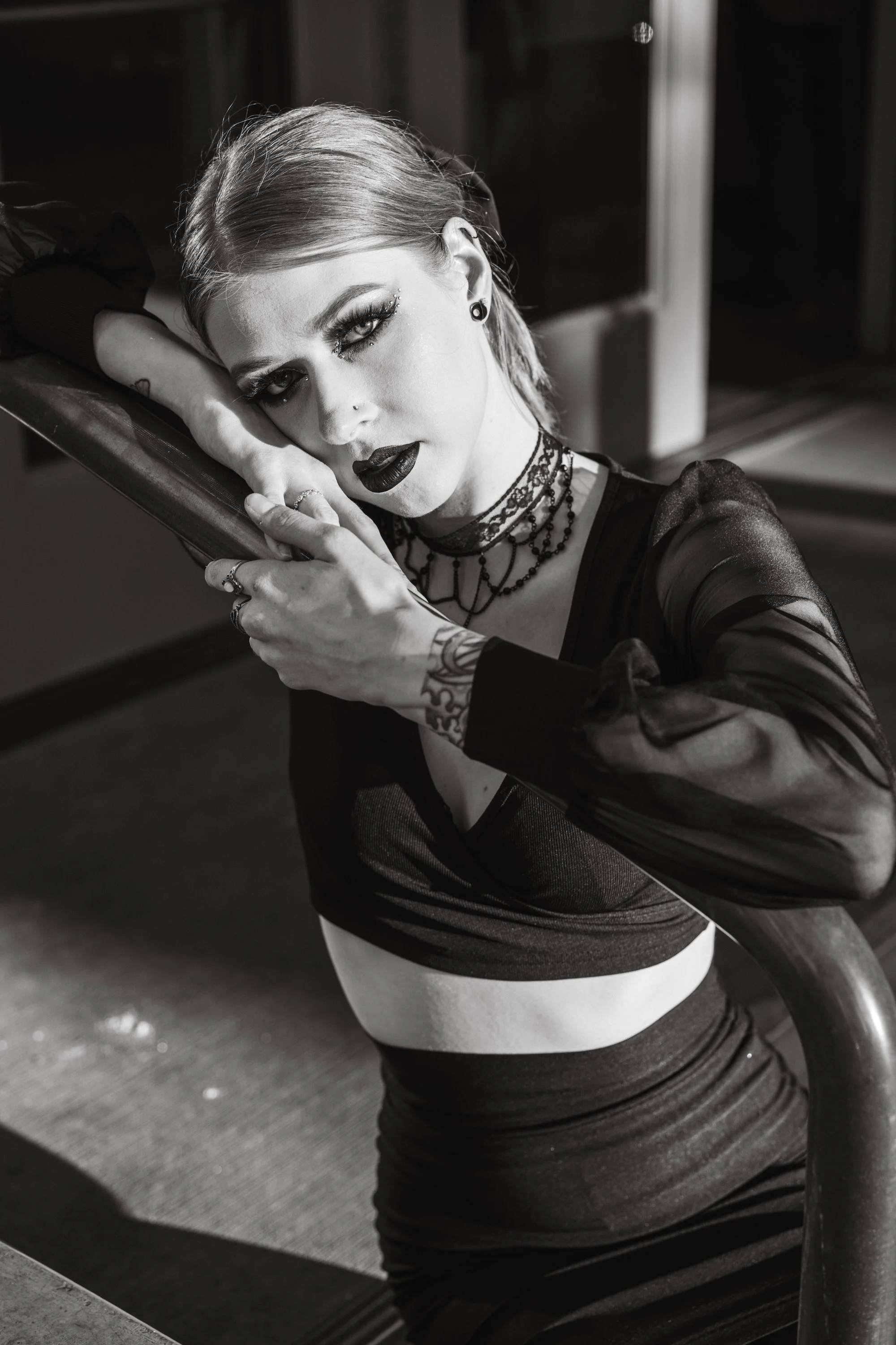 Black and white gothic editorial portrait of woman with dark lipstick and dramatic makeup leaning on a railing, fine art photography by Missoula Montana photographer