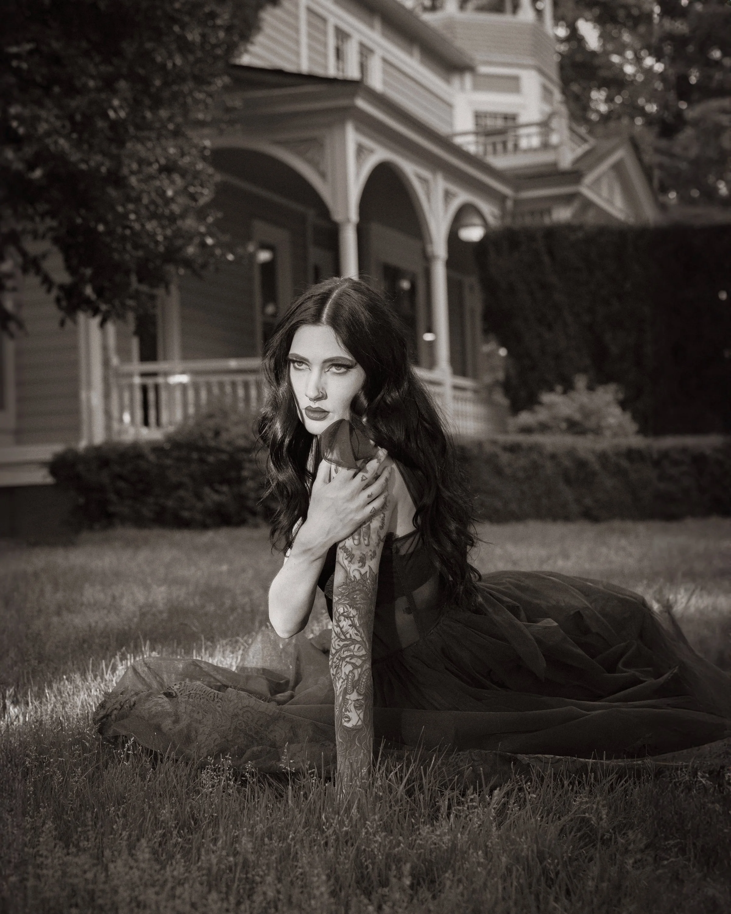 Black and white gothic portrait of woman in dark dress on lawn of Victorian house at night, fine art portrait photography by Missoula Montana photographer