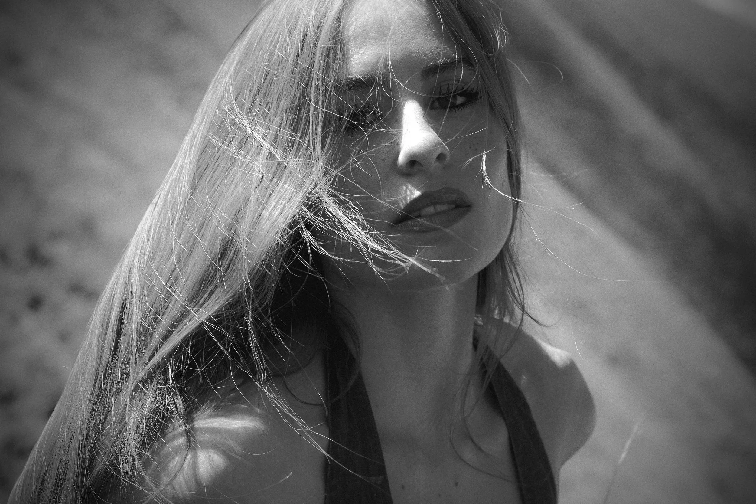 Black and white close up portrait of woman with windswept hair and direct gaze, fine art portrait photography by Missoula Montana photographer.