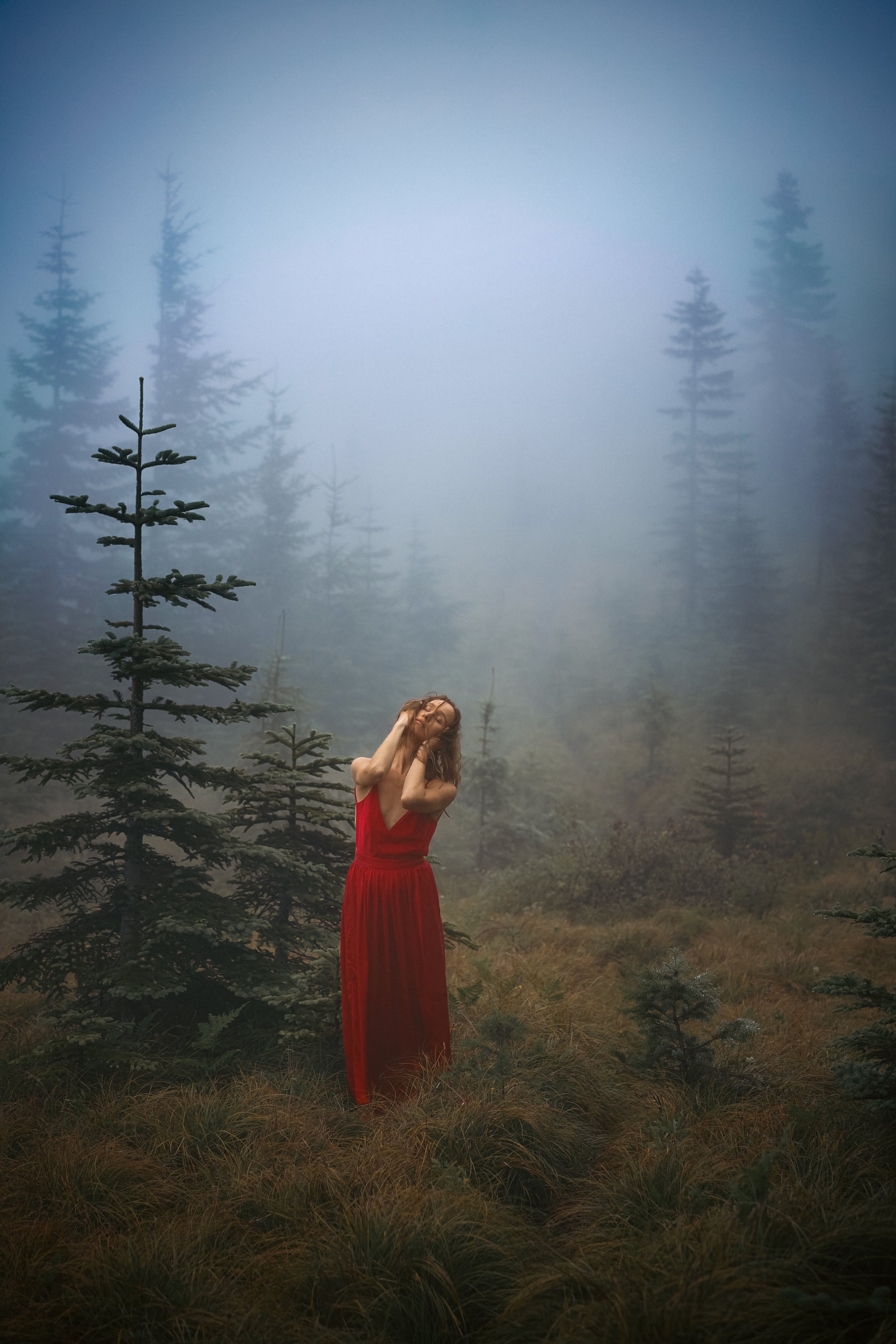 Self portrait of woman in red dress standing in a foggy moody forest, atmospheric fine art nature photography by Montana photographer