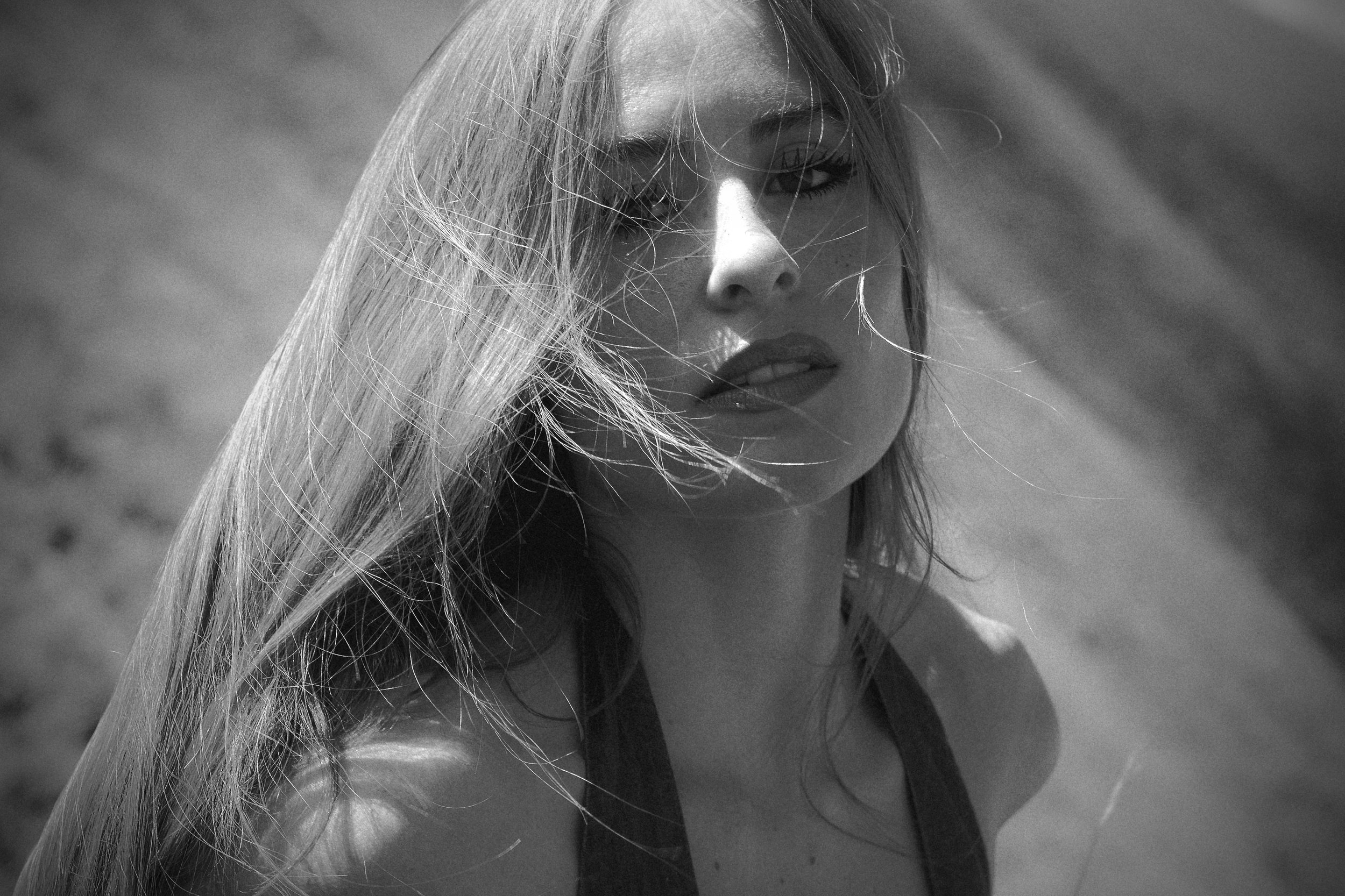 Black and white close up portrait of woman with windswept hair across her face shot on Mt Jumbo Missoula Montana, fine art editorial portrait photography by Missoula photographer