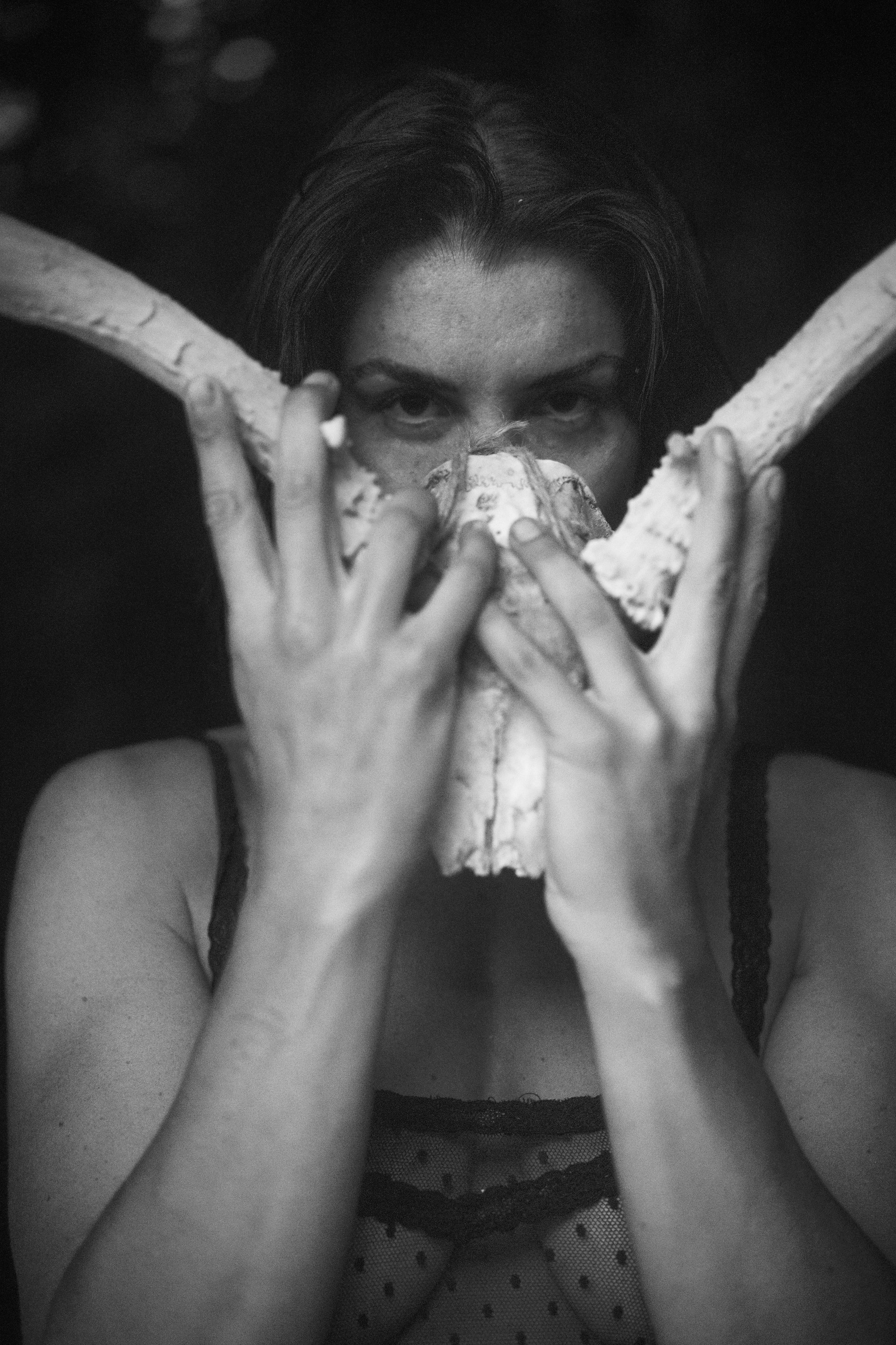 Black and white conceptual portrait of woman holding antlers in front of her face, fine art portrait photography by Missoula Montana photographer