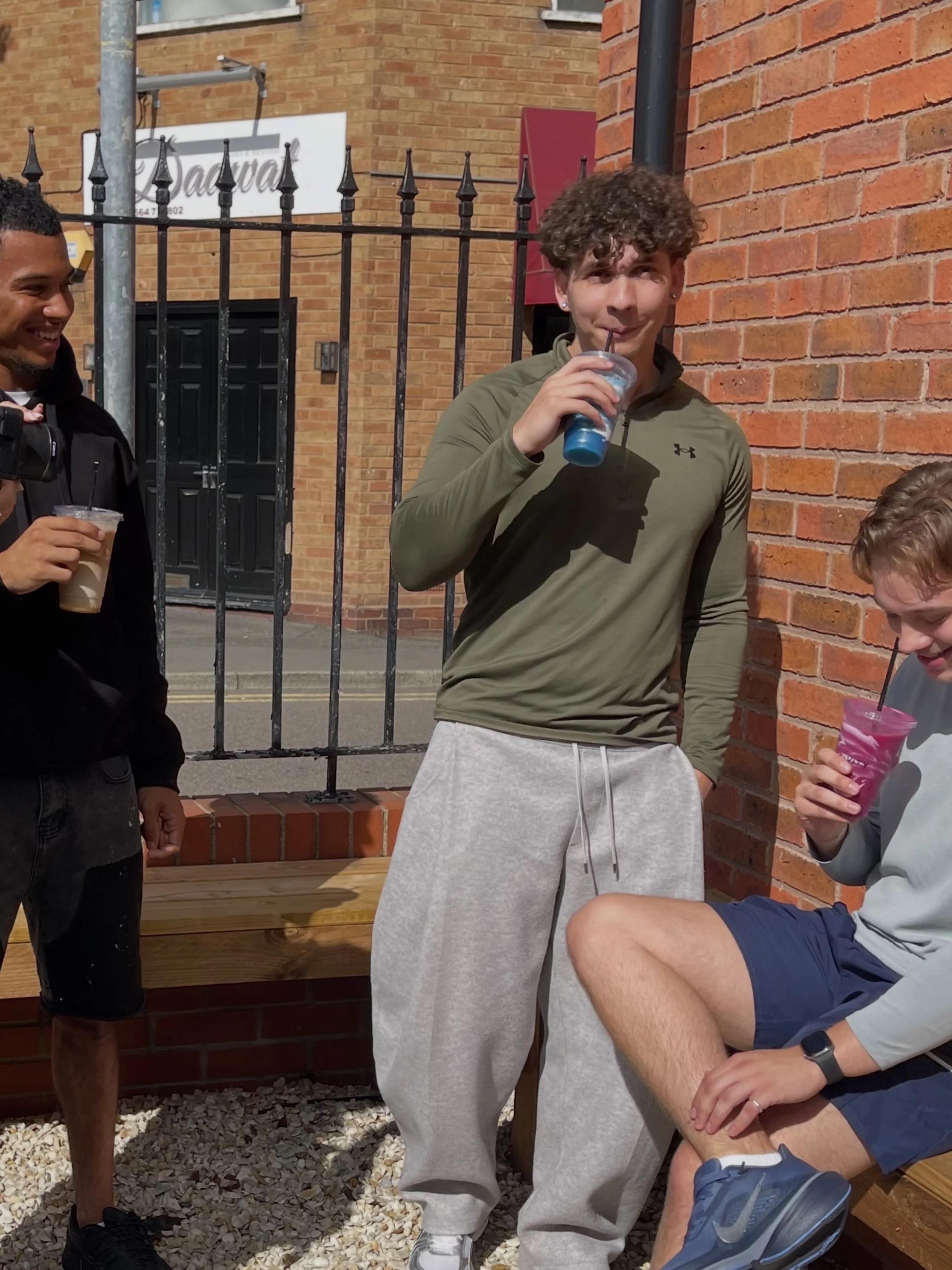Three customers holding Livity drinks outside the shop on a sunny day.