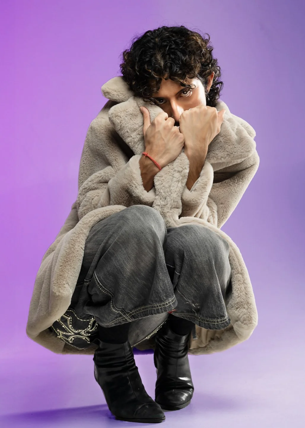 fashion/editorial shoot where model is crouched down and cicerone part of their face with the coat