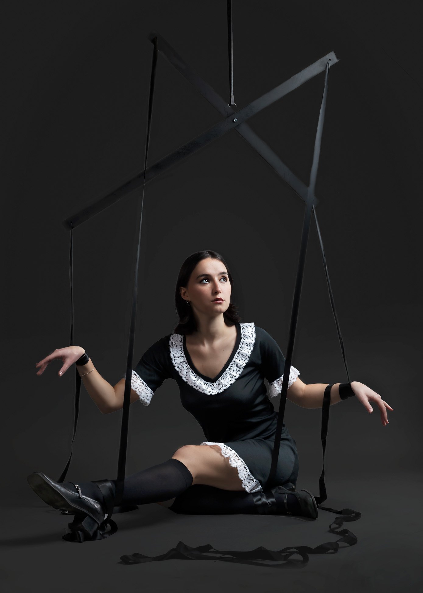 Image depicting a person trapped as if a puppet with a marionette hanging above them indicating someone else is in control.
