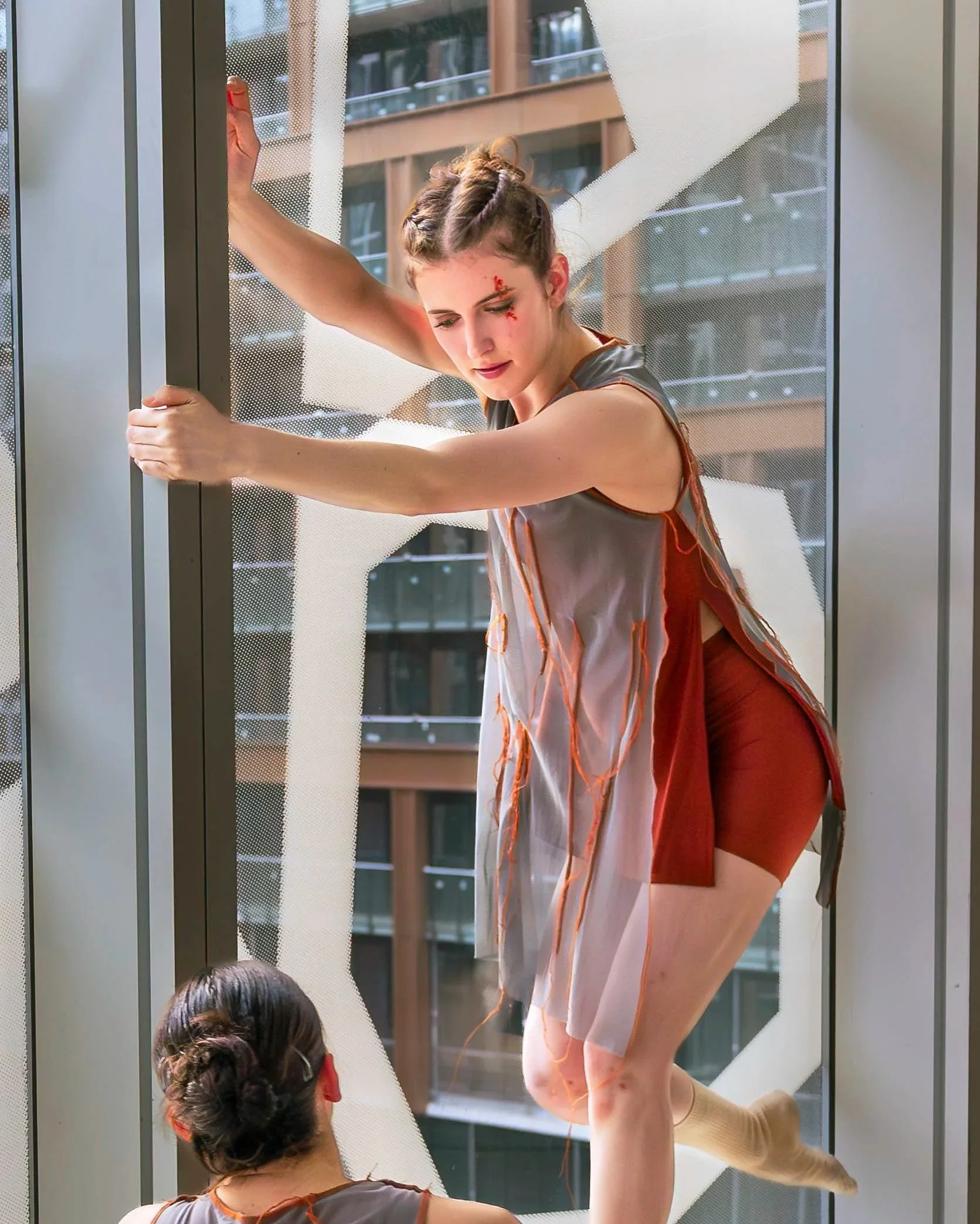 Image capturing a shot during a show. Dancer is bye the window posing and gazing at another dancer