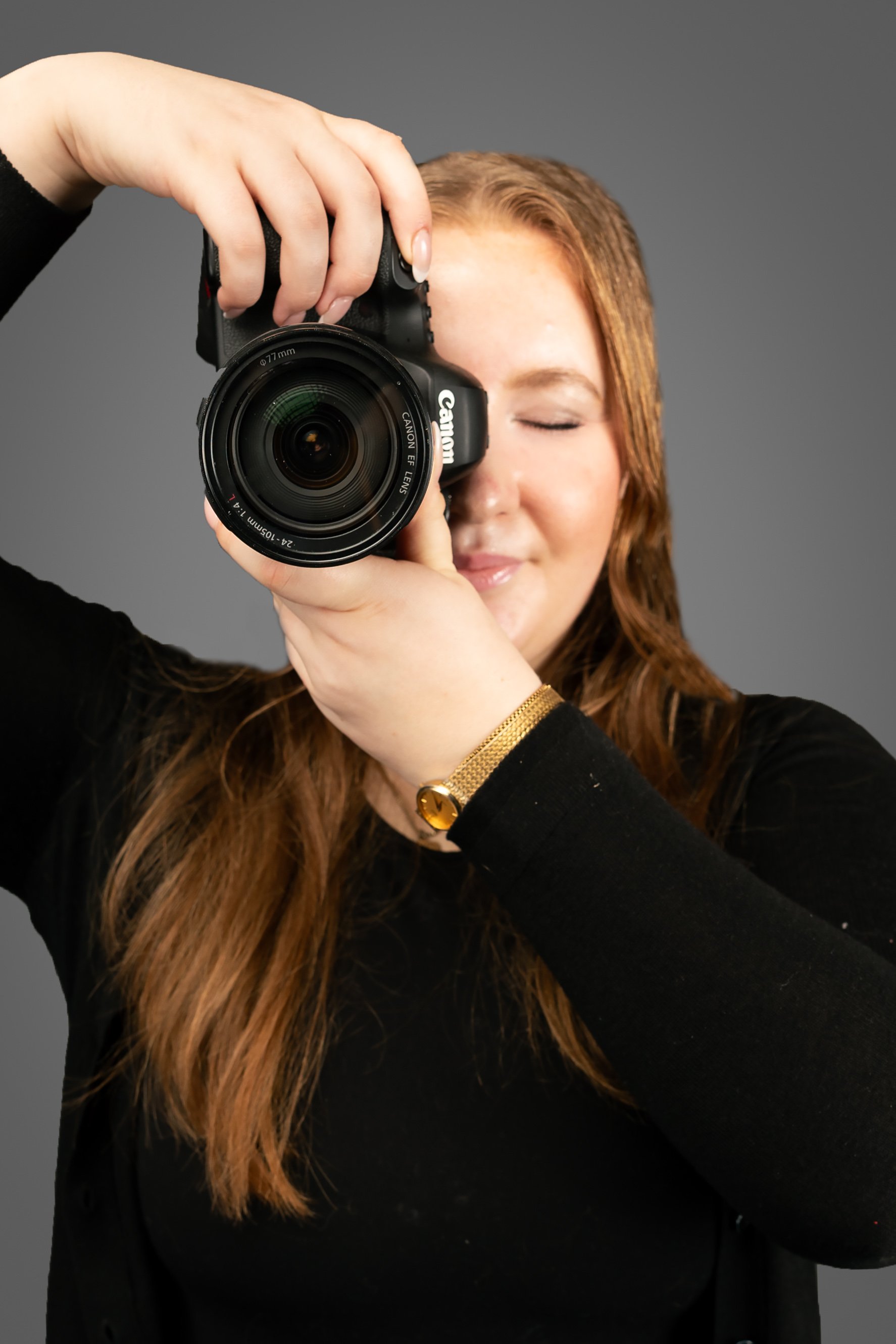 Photo of the photographer, Abigail Plaskett, with her Canon R6 camera as if she is taking a photo