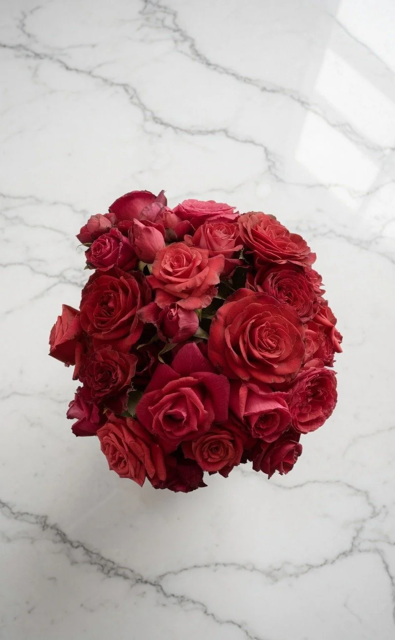 Lush top down view of a romantic bouquet of deep red roses on marble countertop - timeless elegance in full bloom