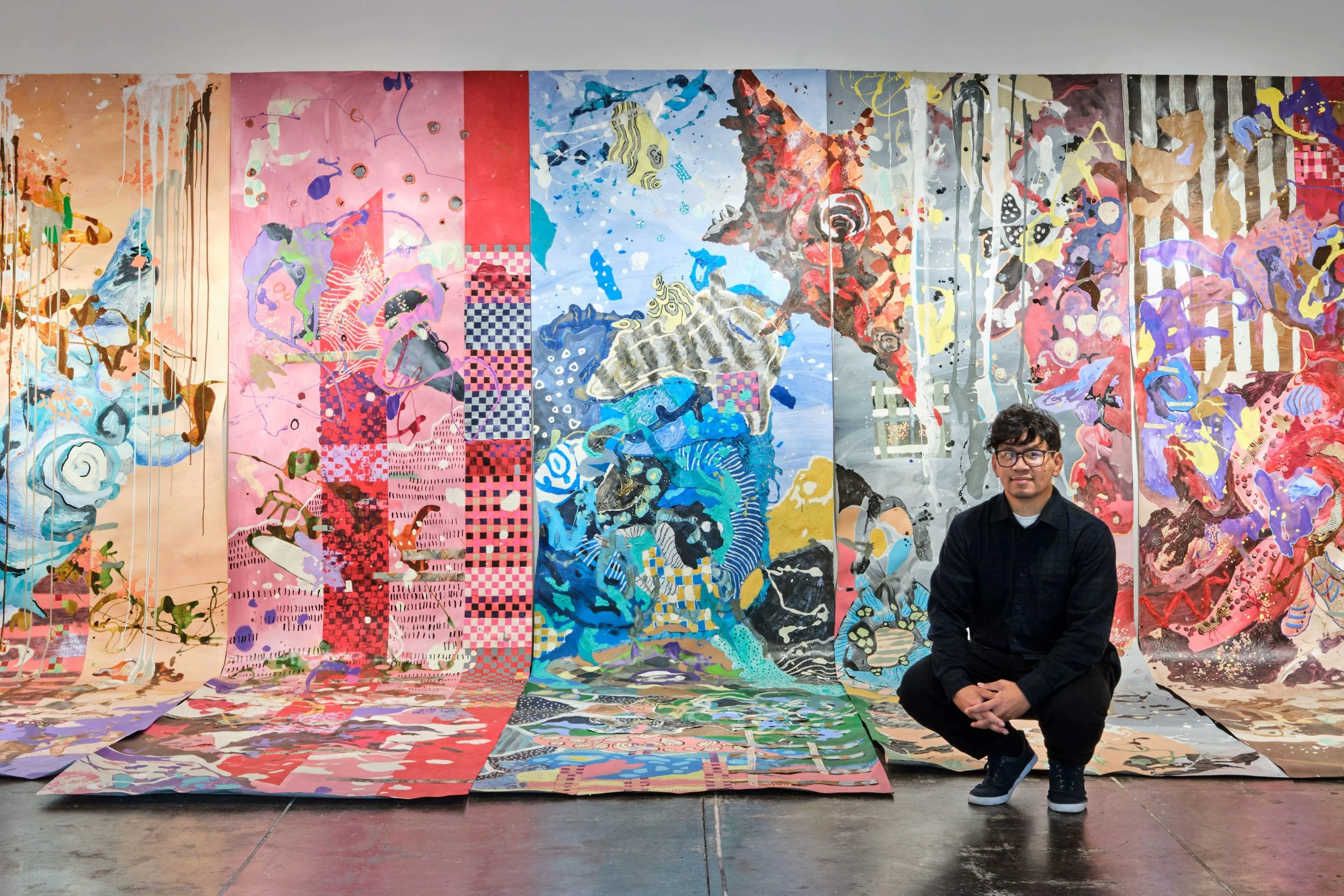 The artist, Sokthea Chan, who stands in front of his large scroll installation piece from the exhibition "A Moment Together".